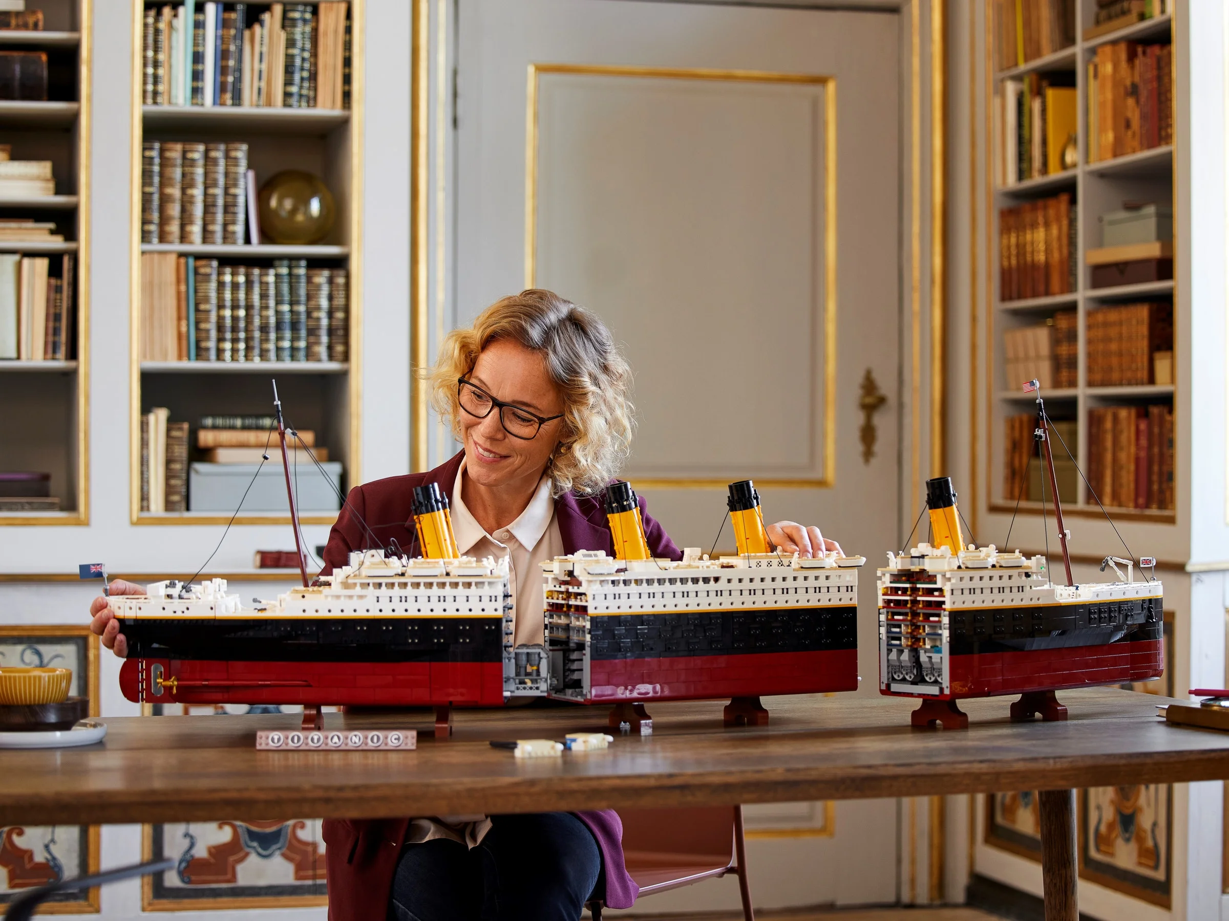 Femeie asamblează modelul LEGO Titanic, prezentând detaliile și secțiunile interne ale navei.