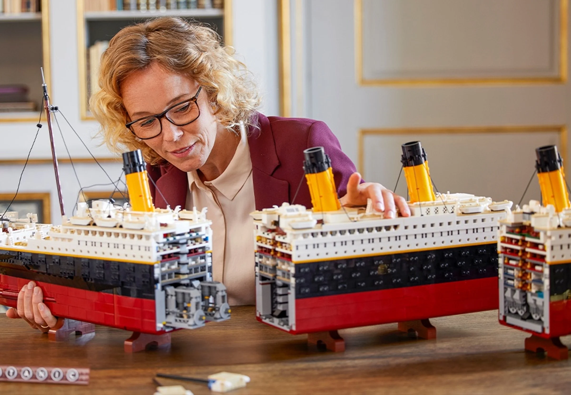 Femeie inspectând secțiunile modelului LEGO Titanic, arătând detaliile interioare.