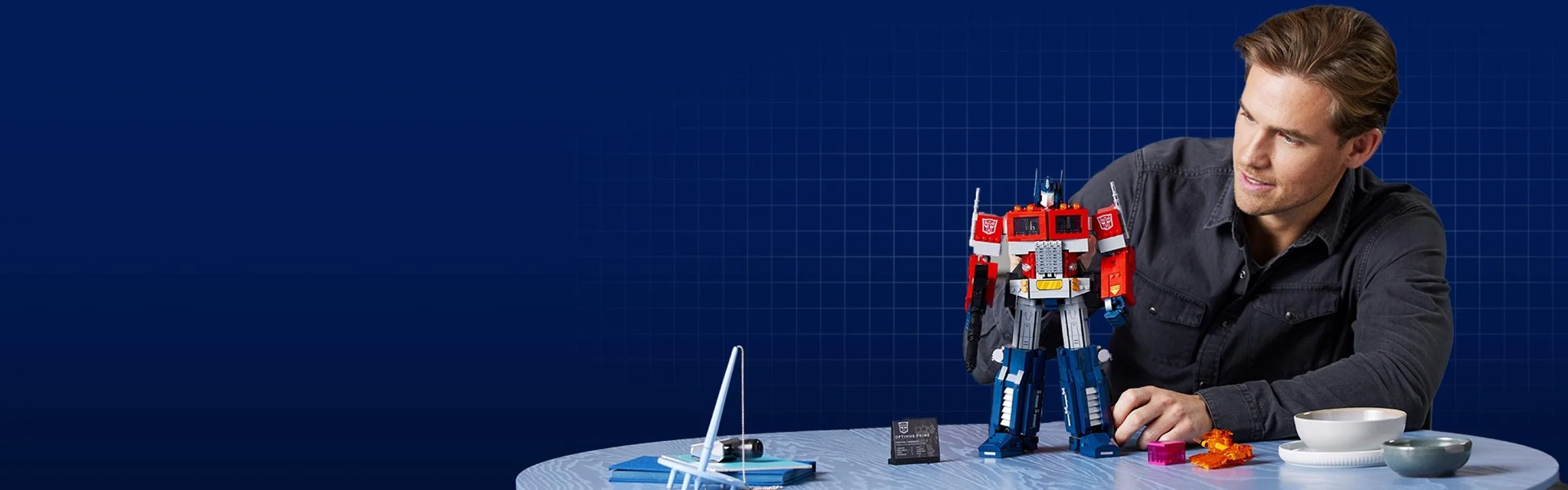 Bărbat construind modelul LEGO Optimus Prime, arătând entuziasmul pentru set.