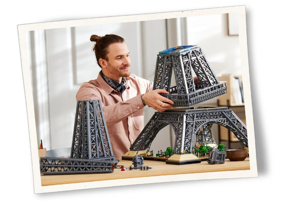 Bărbat construind Turnul Eiffel LEGO, etape de construcție vizibile. Set detaliat, experiență plăcută.
