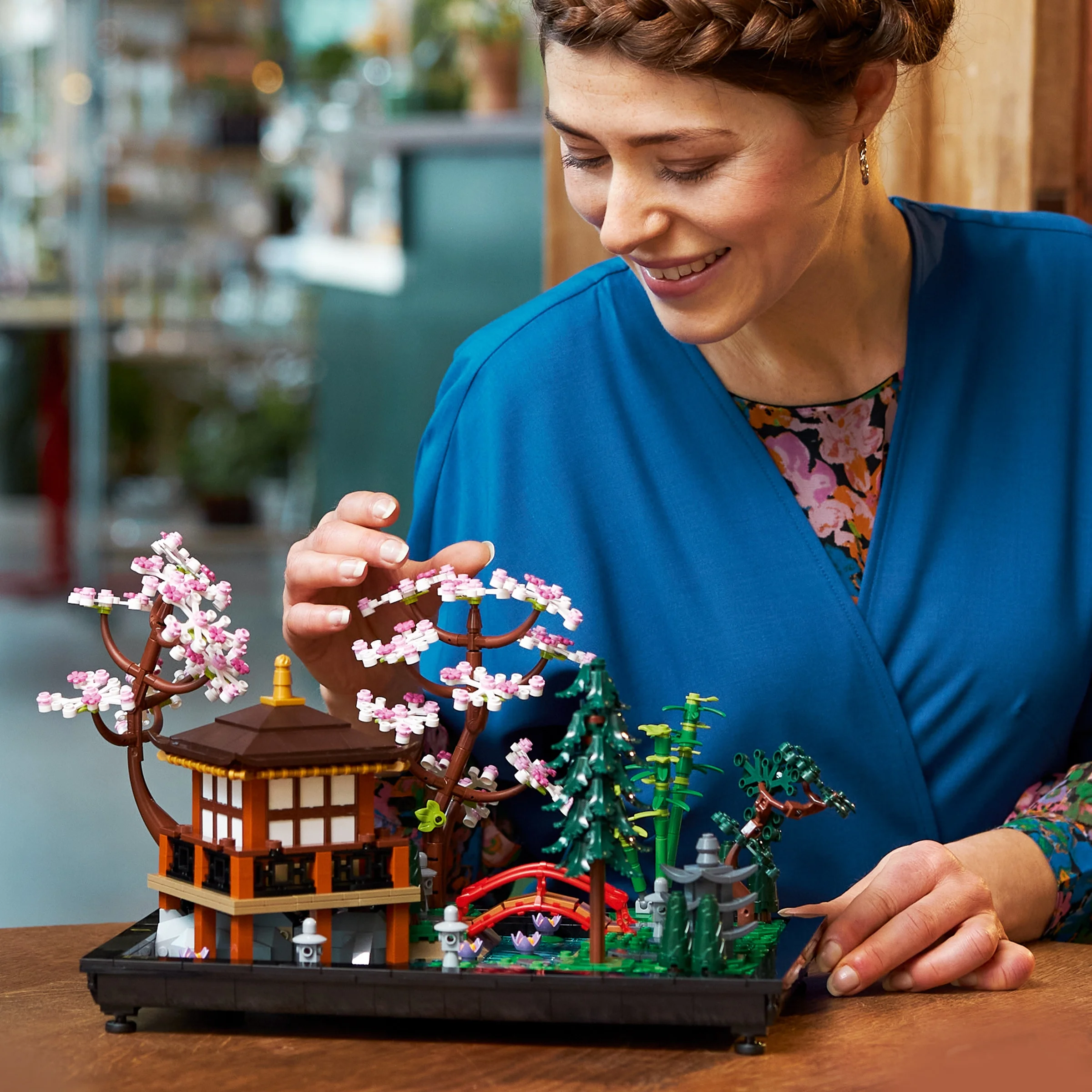 Femeie admirând grădina LEGO Tranquil Garden (10315). O imagine relaxantă și detaliată a modelului.