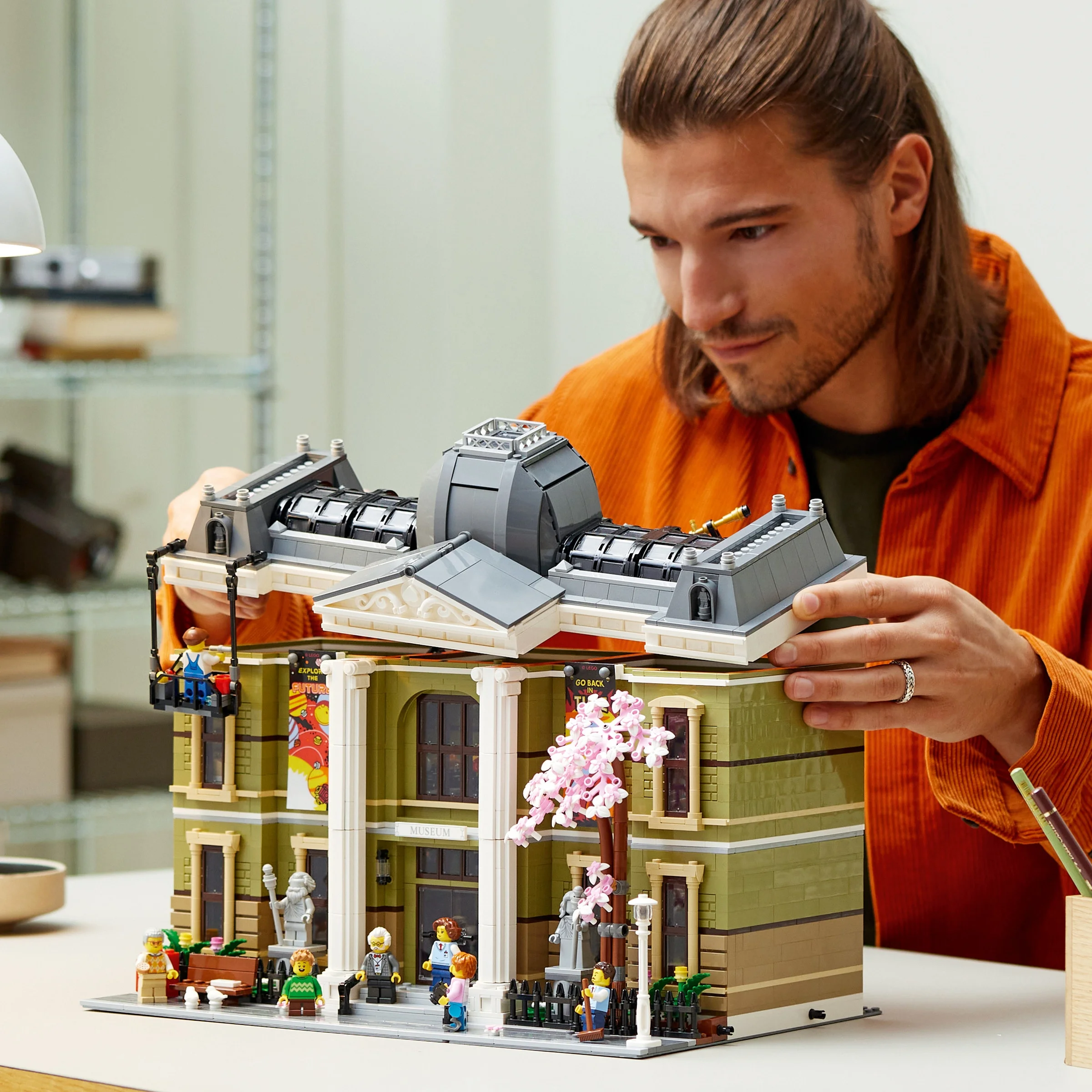 Imagine cu un tânăr construind Muzeul de Istorie Naturală LEGO 10326, concentrându-se pe asamblare.