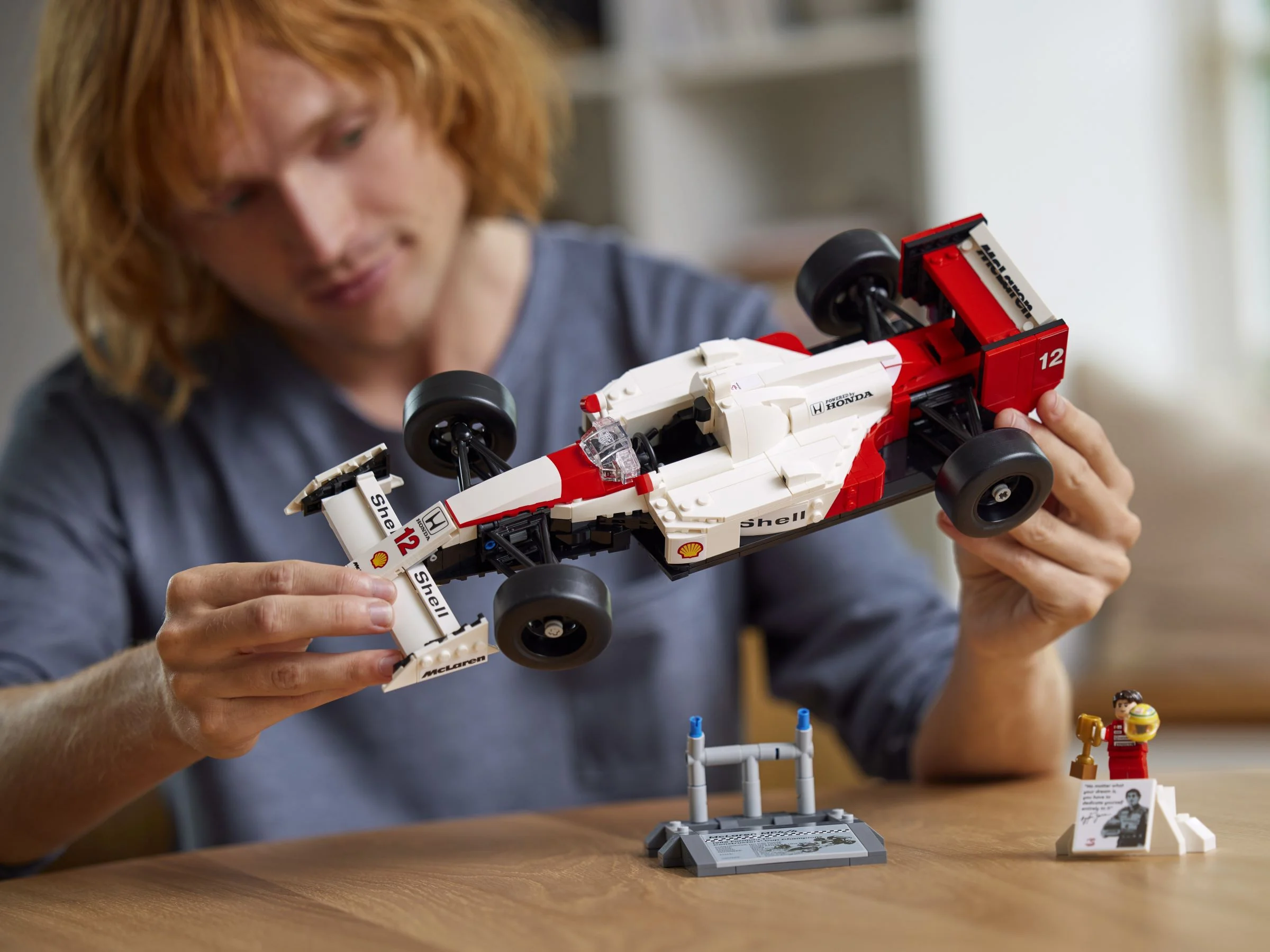 Un bărbat admiră modelul McLaren MP4/4, cu minifigurina Ayrton Senna lângă.
