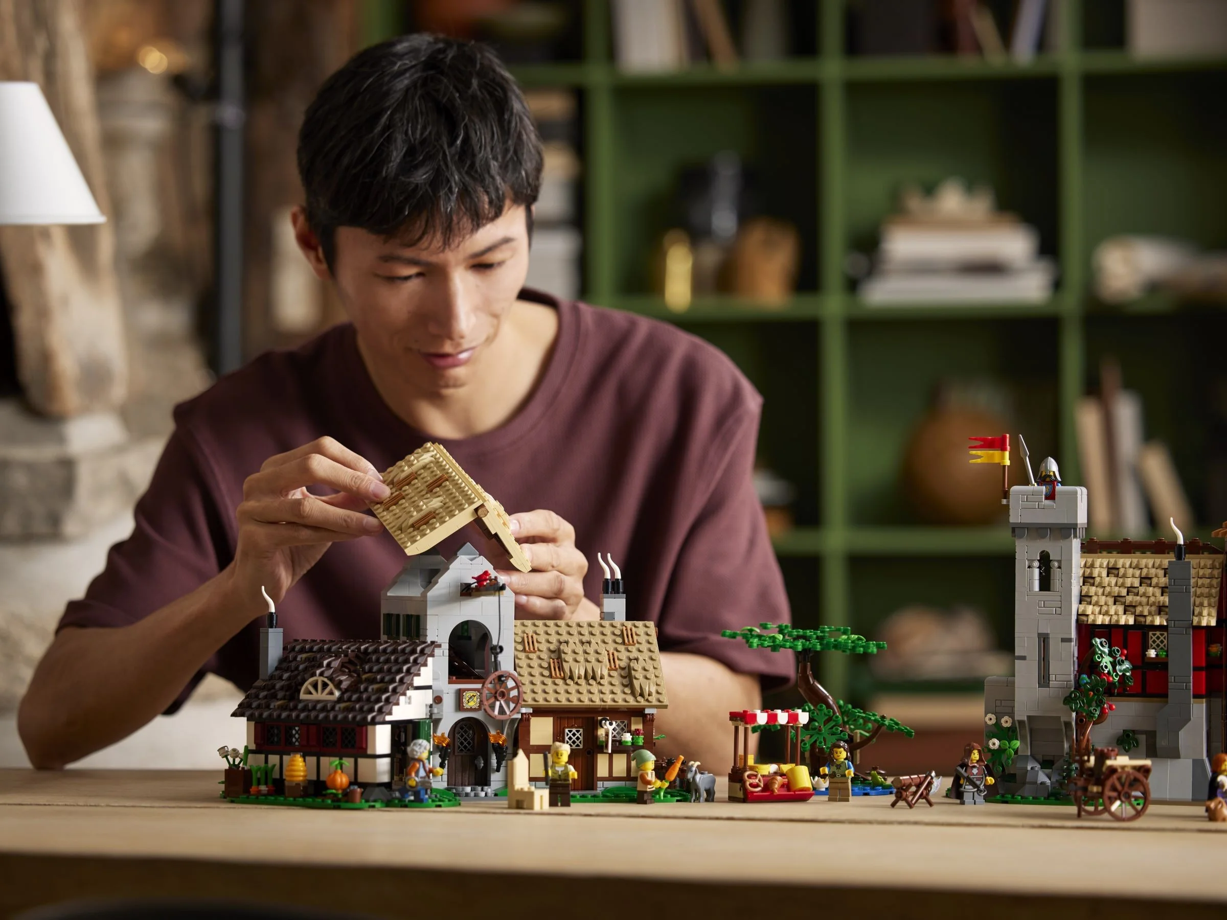 Un bărbat construiește acoperișul LEGO al pieței medievale, setul 10332.