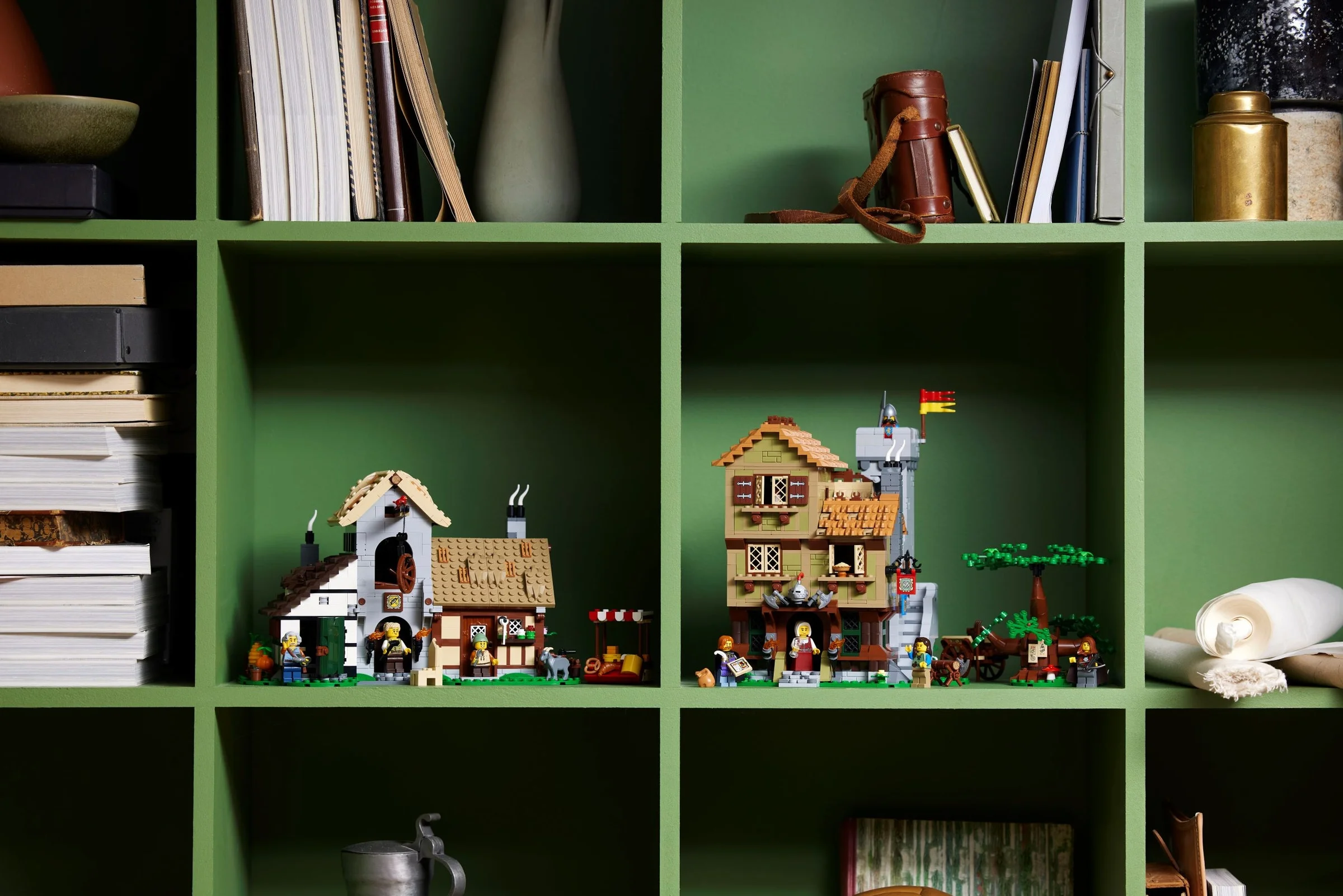 Imagine cu setul LEGO 10332, prezentat pe rafturi verzi, alături de alte obiecte decorative.