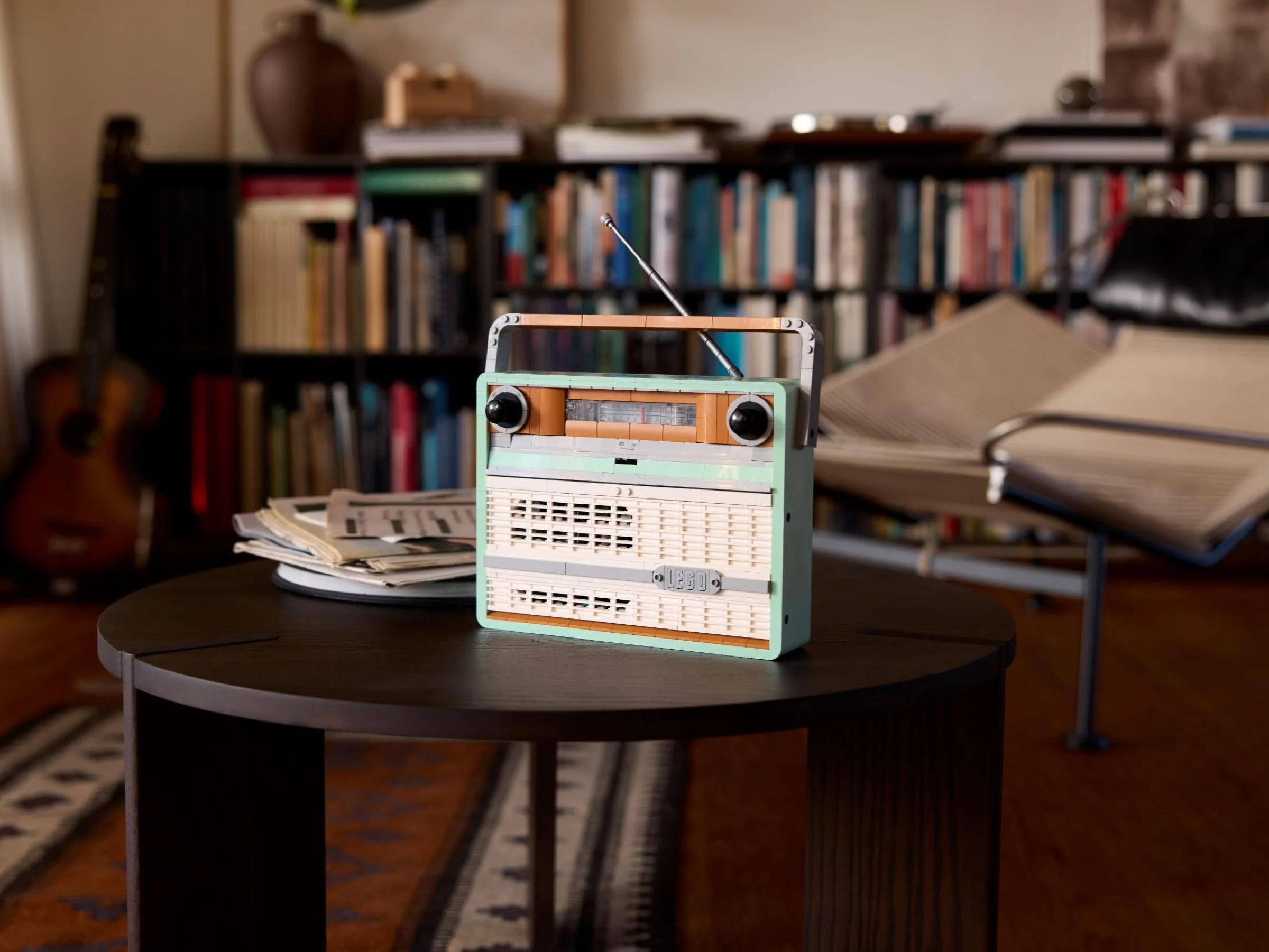 Radioul retro LEGO 10334 expus într-un decor casnic, pe o măsuță, cu cărți și mobilier în fundal.