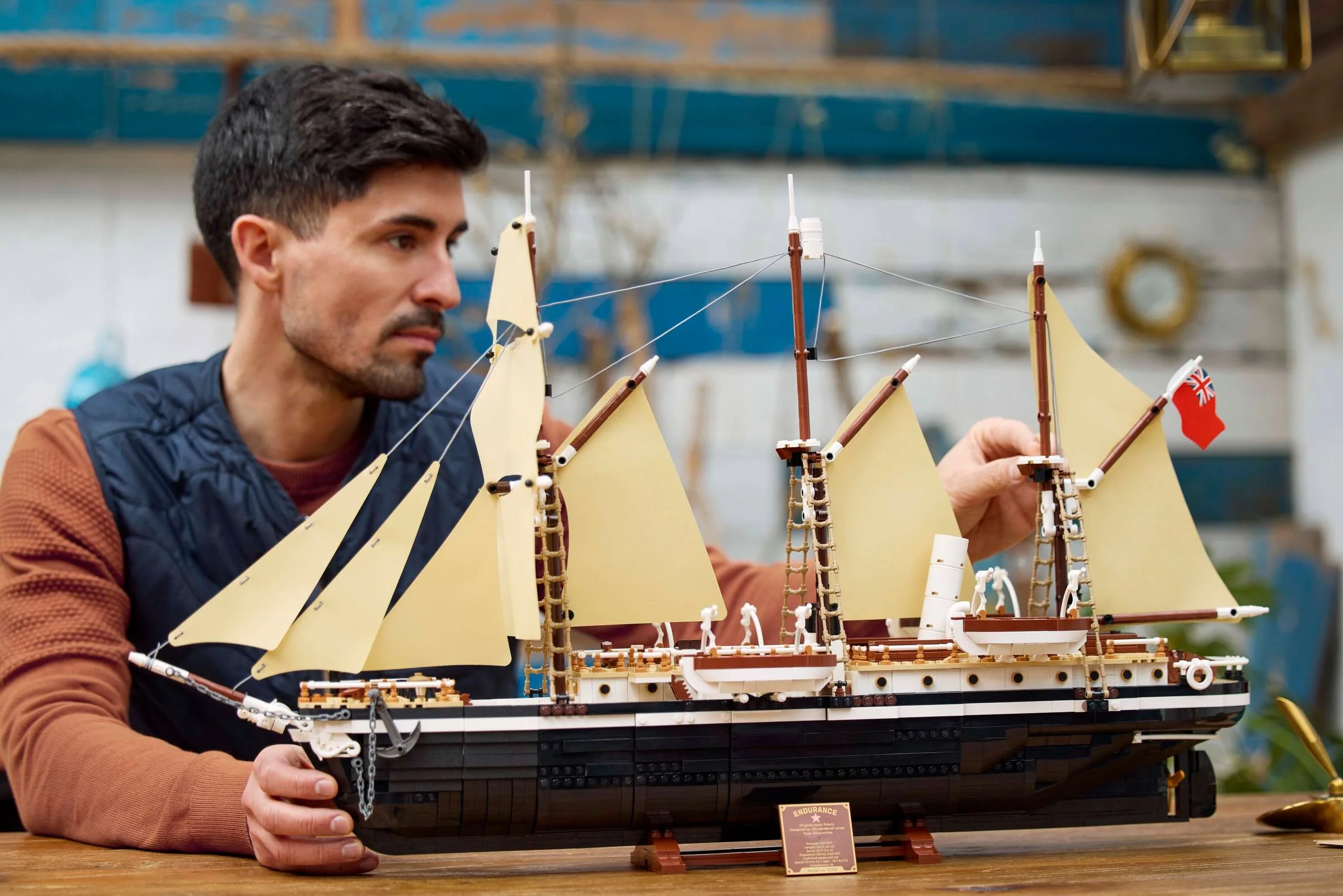 Bărbat admirând nava Endurance LEGO 10335. Model detaliat cu pânze bej și steag britanic.