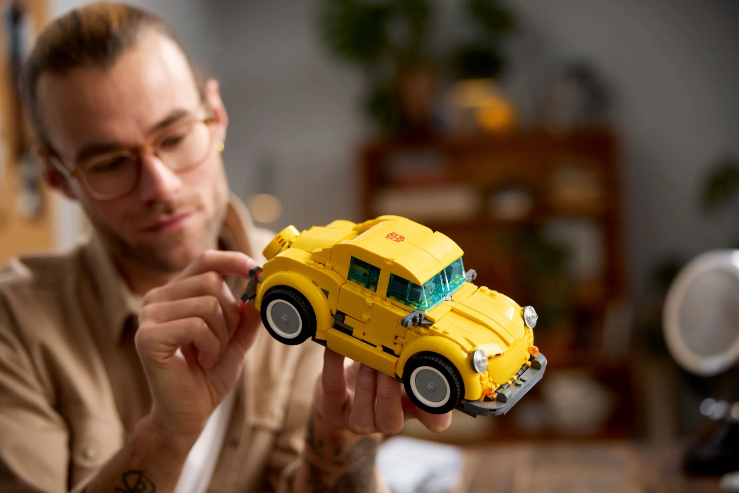 Bărbat arată mașina Bumblebee LEGO, galbenă și detaliată, concentrându-se pe design.
