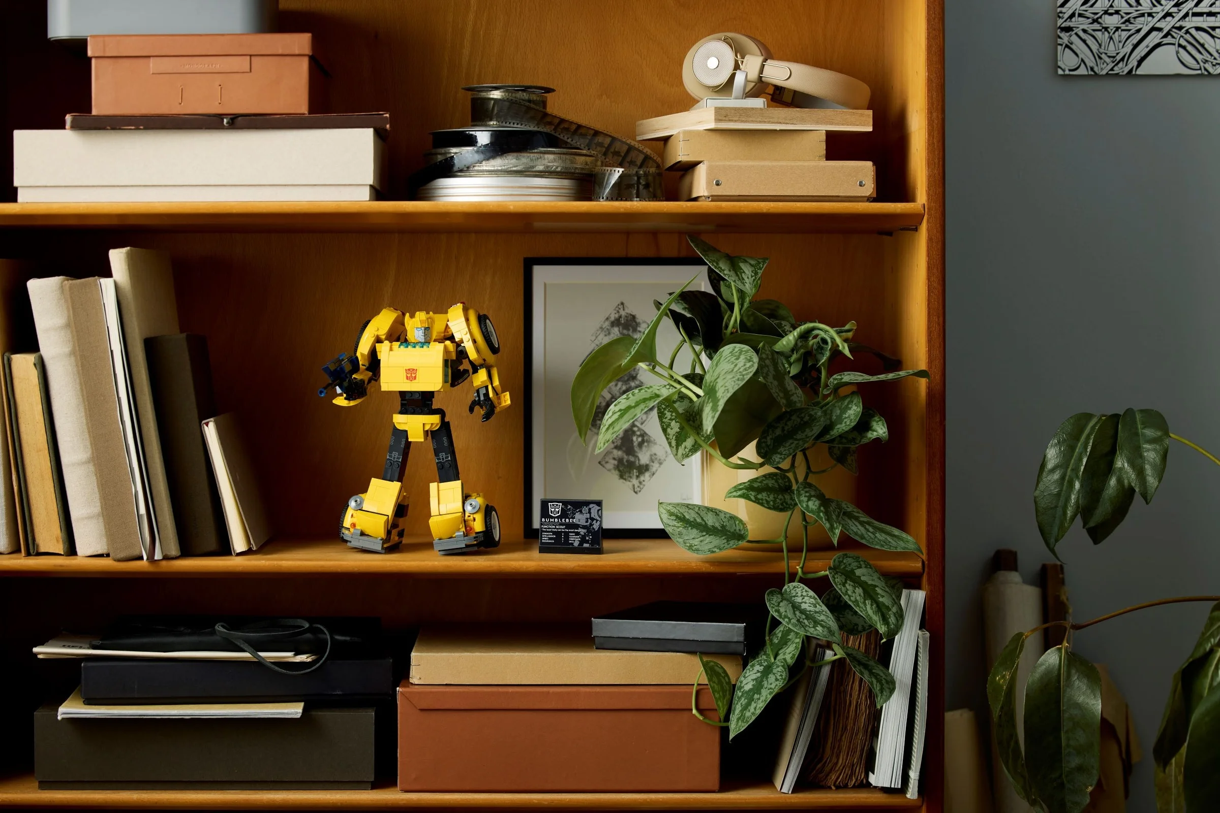 Bumblebee LEGO, robot galben, pe un raft cu cărți și alte obiecte de decor.