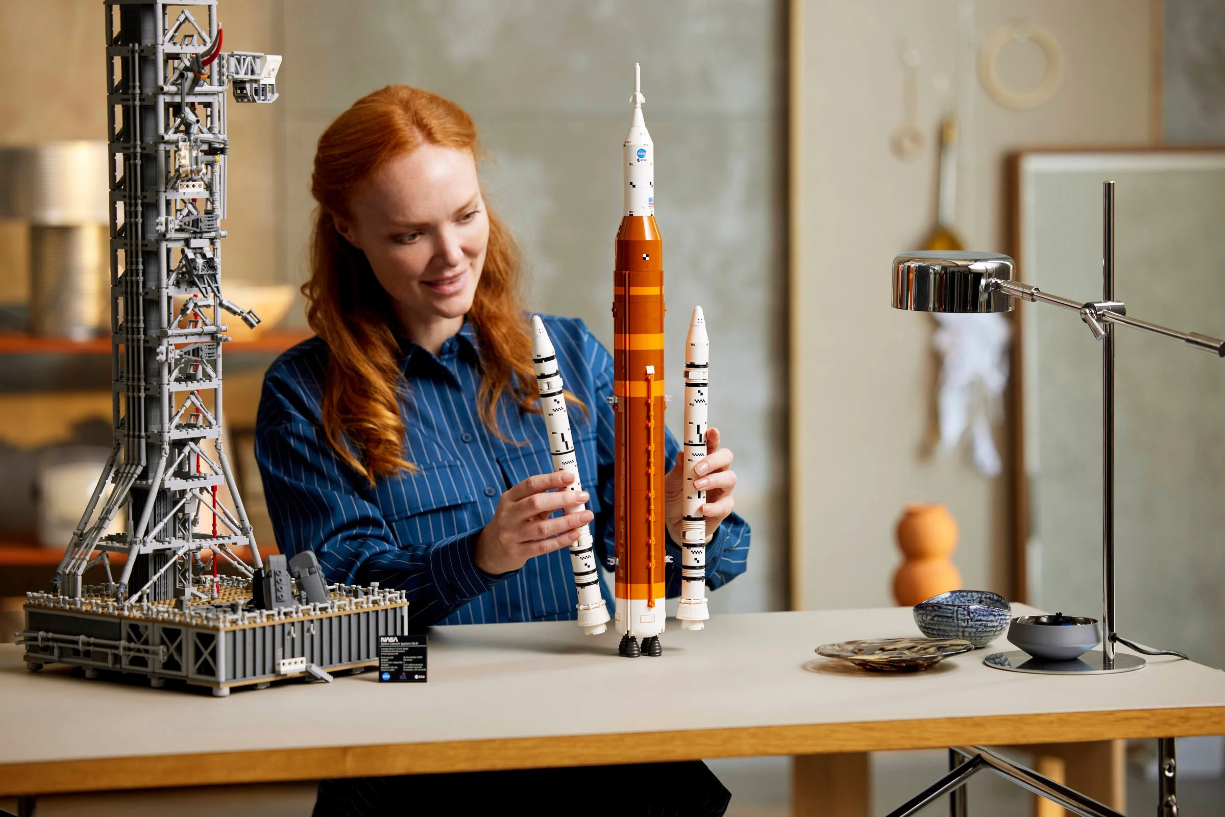 Femeie admirând macheta LEGO a sistemului NASA Artemis Space Launch System, cu racheta și turnul.