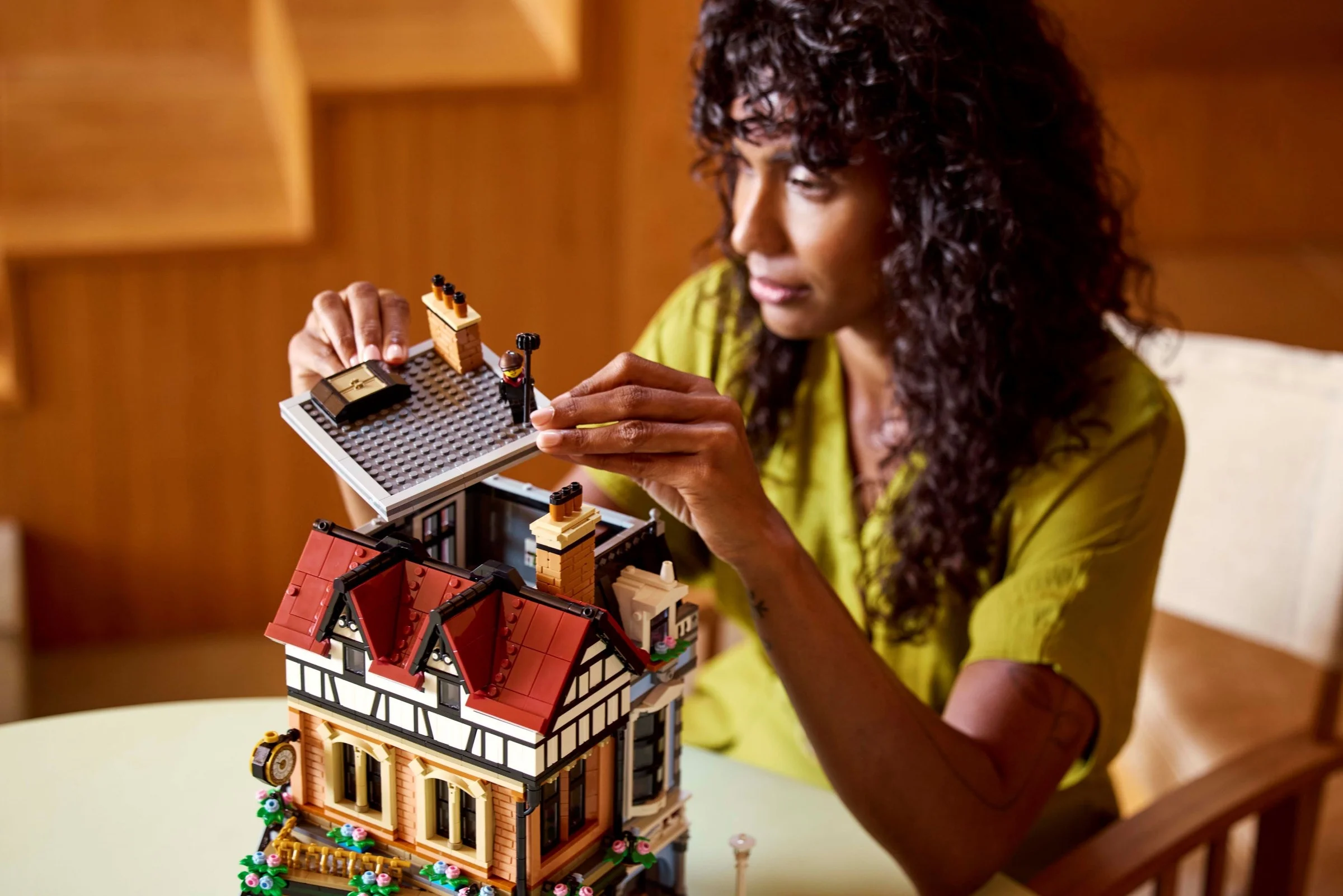 Femeie construind setul LEGO 10350 Tudor Corner. Scenă cu modelul parțial asamblat.