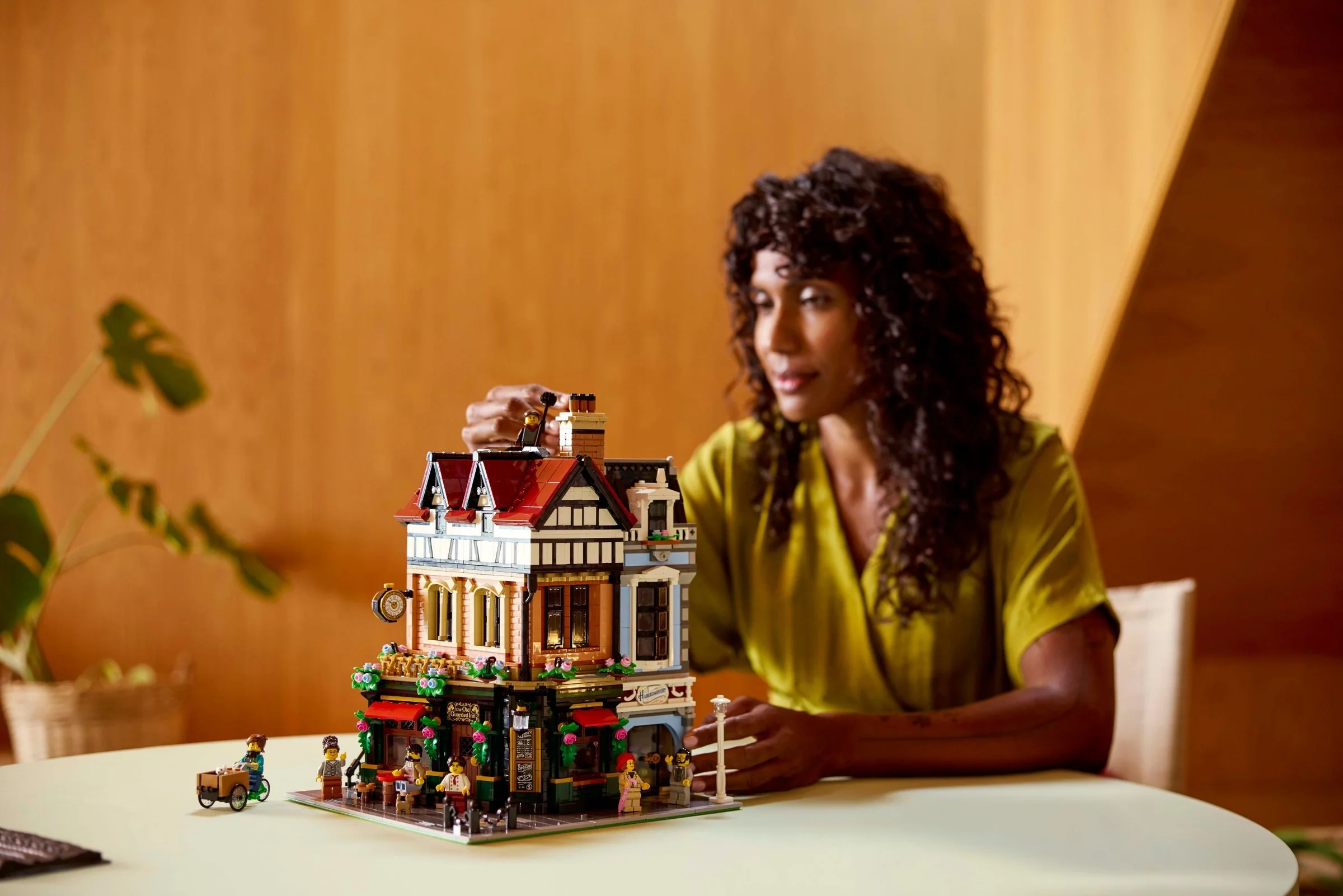 Imagine cu modelul LEGO Tudor Corner 10350 și o femeie interacționând cu acesta.