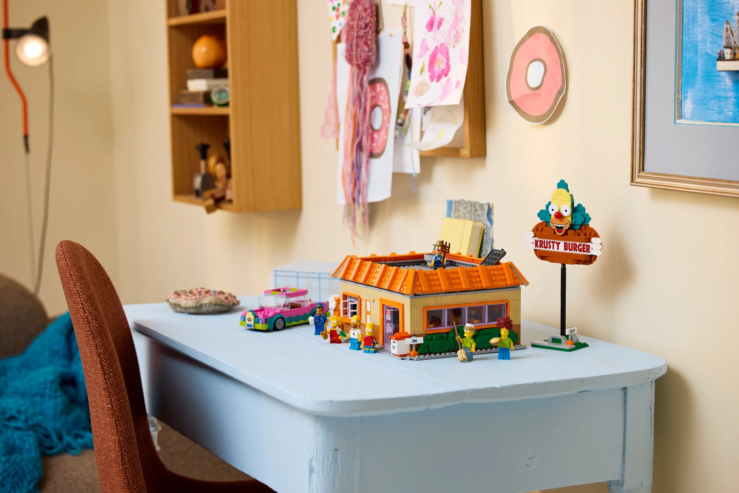 Setul LEGO Krusty Burger pe un birou, prezentând restaurantul și minifigurinele Simpsons.