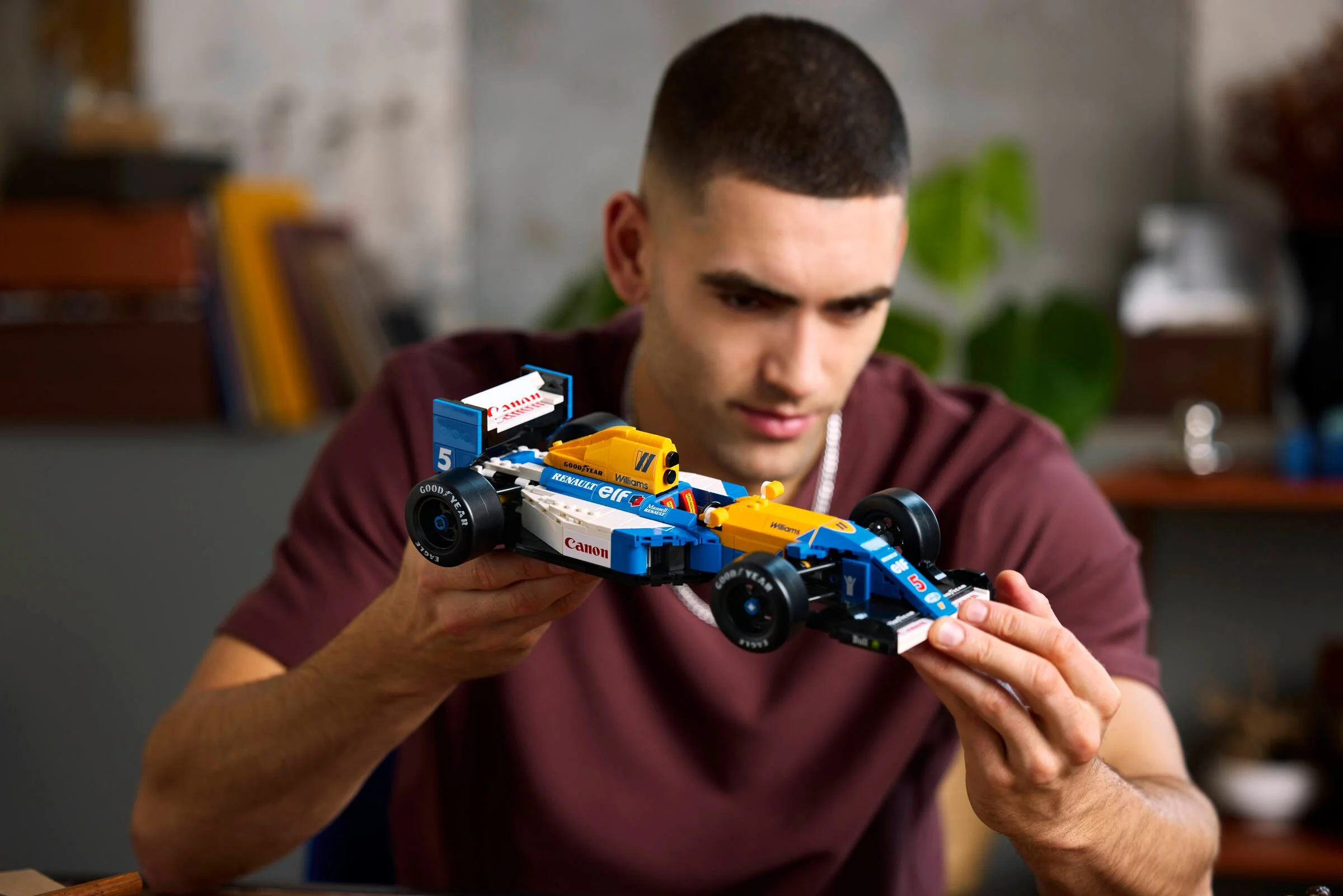 Un bărbat ține în mâini modelul LEGO Williams FW14B, admirând detaliile.