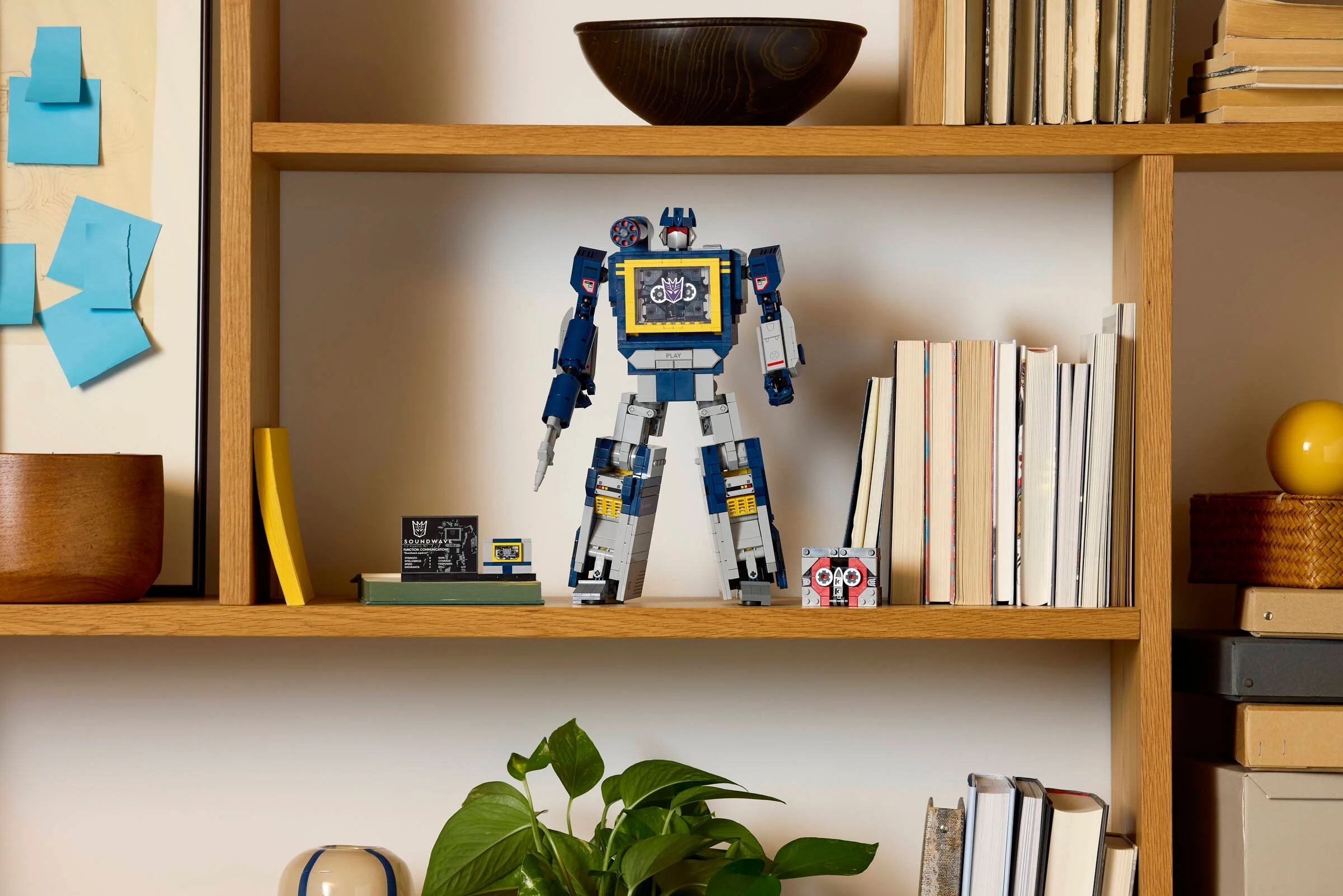 Setul LEGO 10358 Transformers Soundwave expus pe o etajeră, alături de o casetă și o placă informativă.