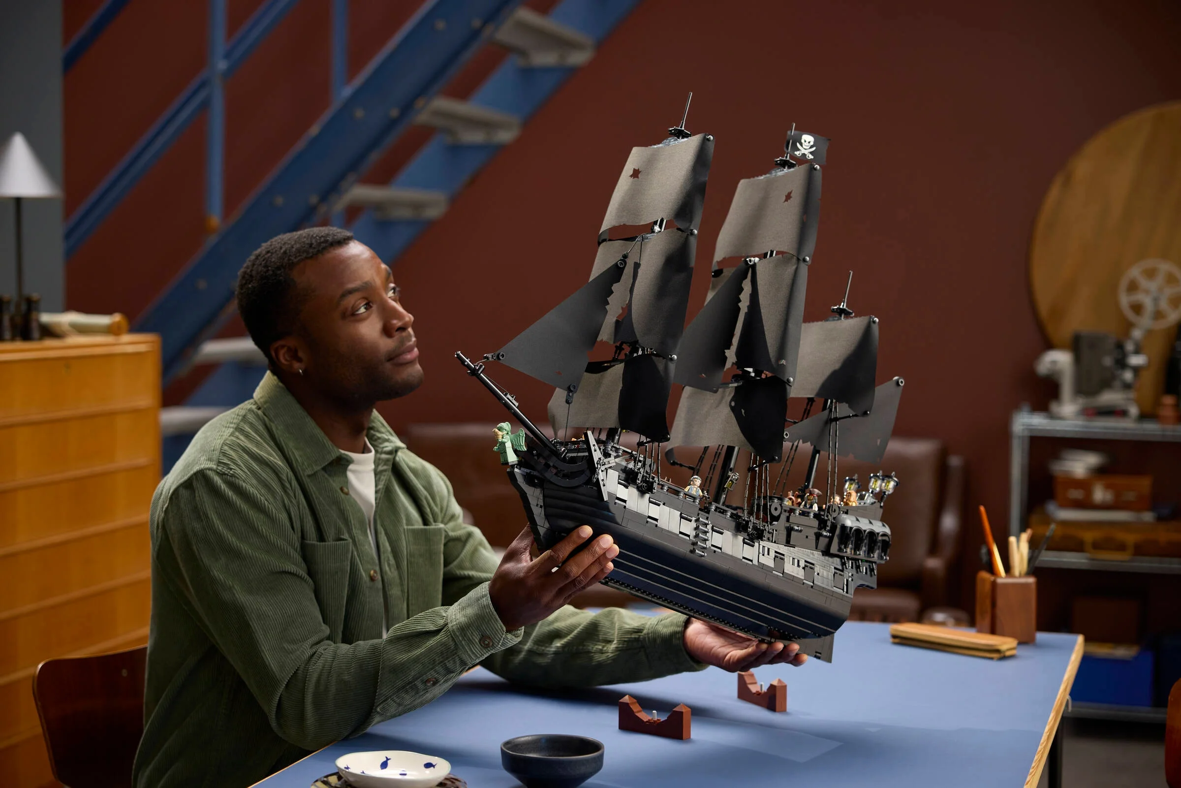 Bărbat admirând corabia pirat Captain Jack Sparrow, o construcție LEGO detaliată.