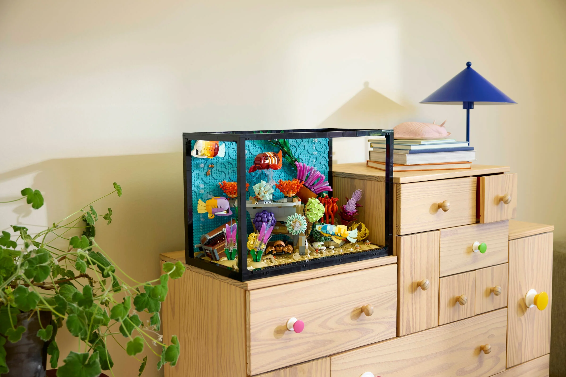 Așezat pe un dulap, acvariul tropical LEGO 10366 încântă privirea cu pești colorați și corali.