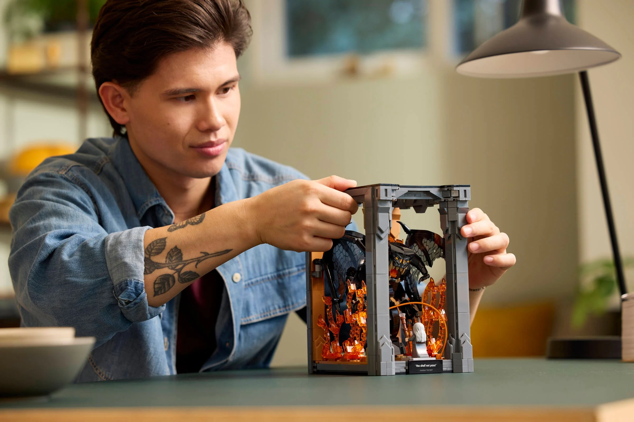 Un tânăr construiește setul LEGO Balrog Book Nook, arătând o scenă detaliată din Lord of the Rings.
