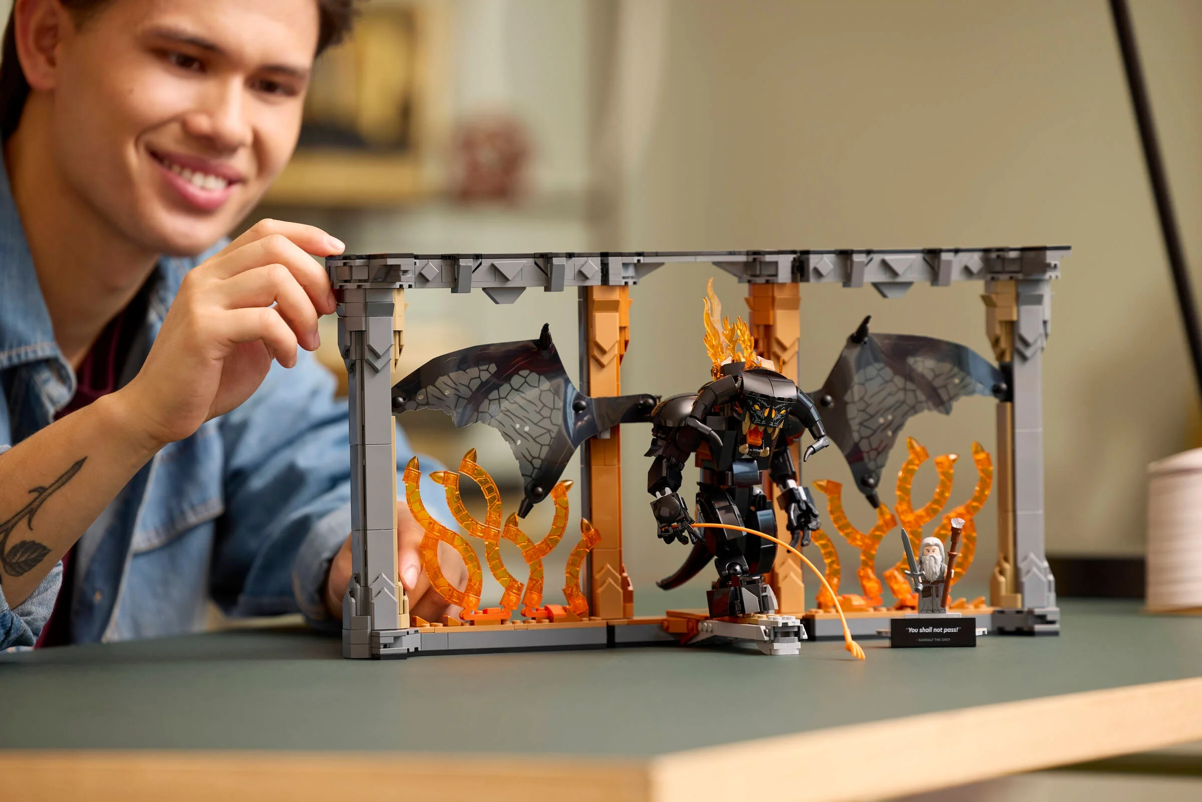 Un tânăr zâmbitor admiră setul LEGO Balrog Book Nook, o dioramă detaliată din LotR.