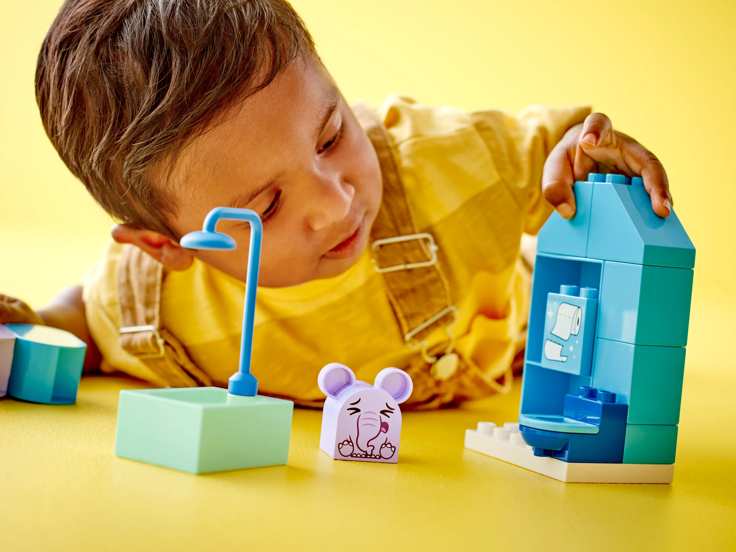 Un copil se joacă cu setul LEGO Duplo 10413. Scenă interactivă cu elemente pentru baie, colorată.