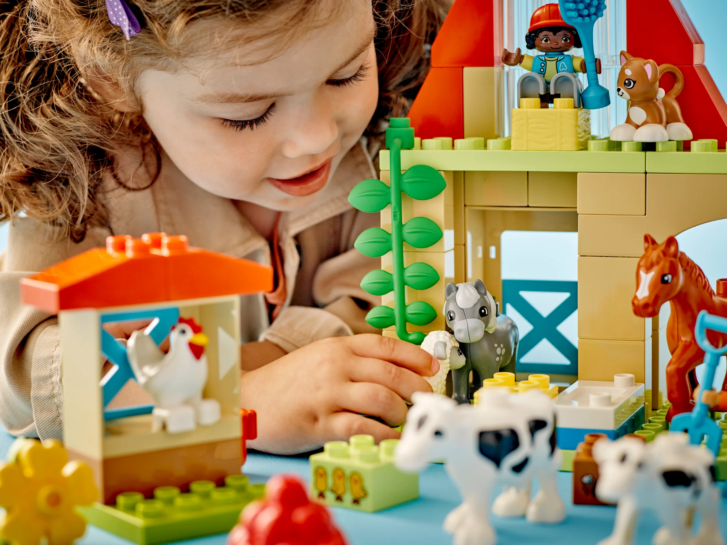 O fetiță se joacă cu setul LEGO Duplo Fermă, îngrijind animalele. Set colorat, atractiv.