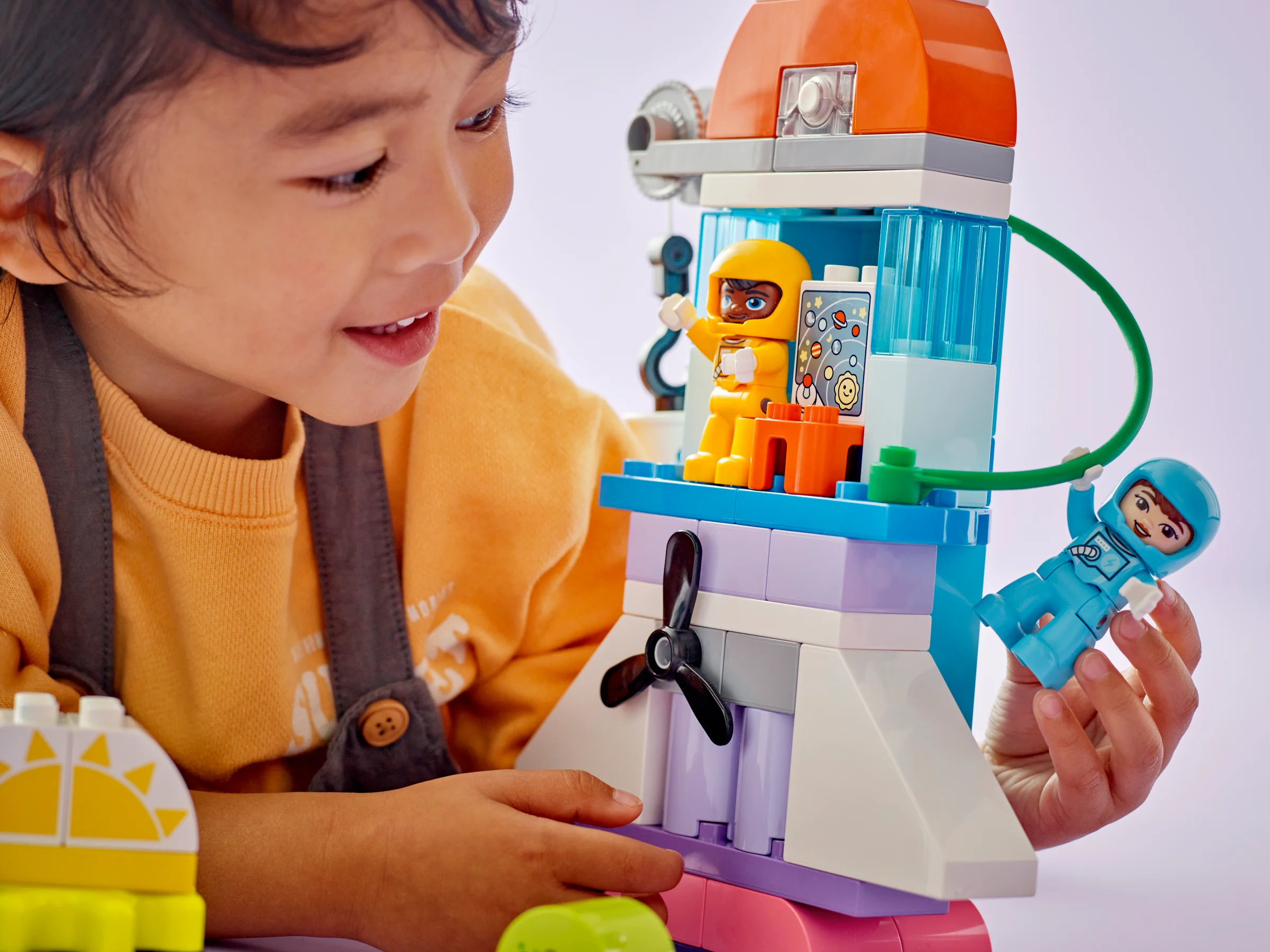 Copil interacționând cu un model LEGO Duplo, explorând imaginația și creativitatea spațială.
