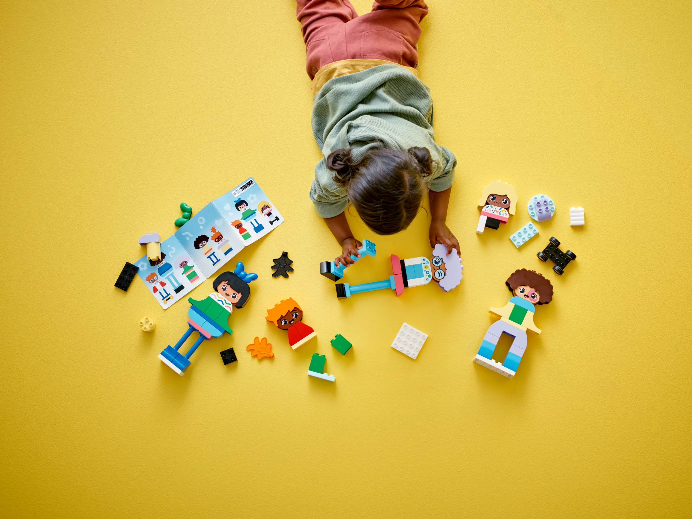 O fetiță se joacă cu setul LEGO DUPLO 10423, construind personaje cu emoții.