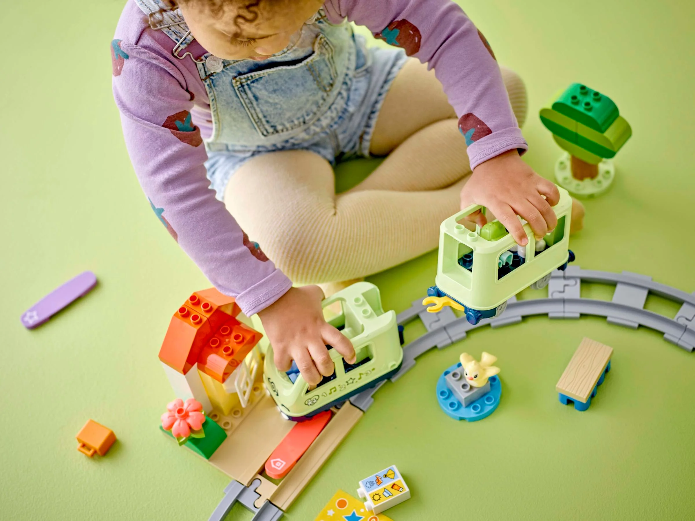 Copil se joacă cu trenul Duplo, explorând vagoanele și traseul interactiv.