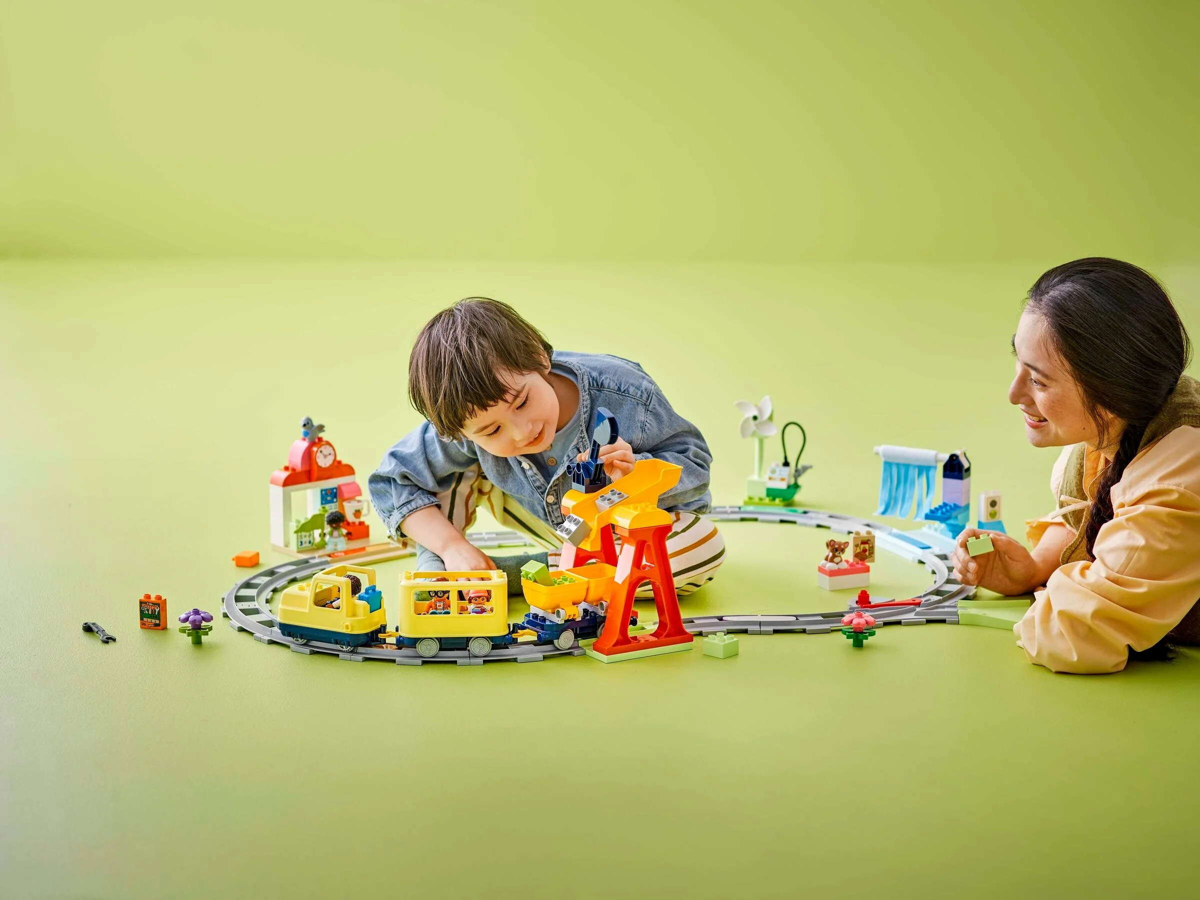 Copil și adult se joacă cu trenul Duplo, explorând funcțiile interactive ale setului.