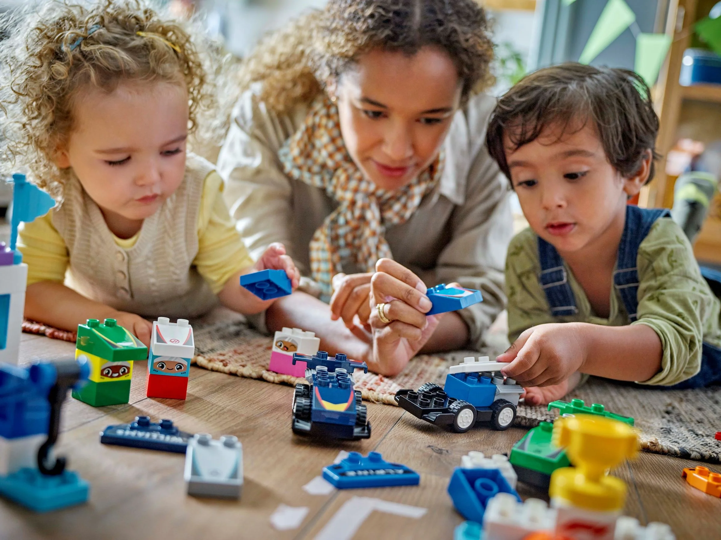 Copii și un adult construind mașini de curse Duplo. Joacă creativă și distractivă.