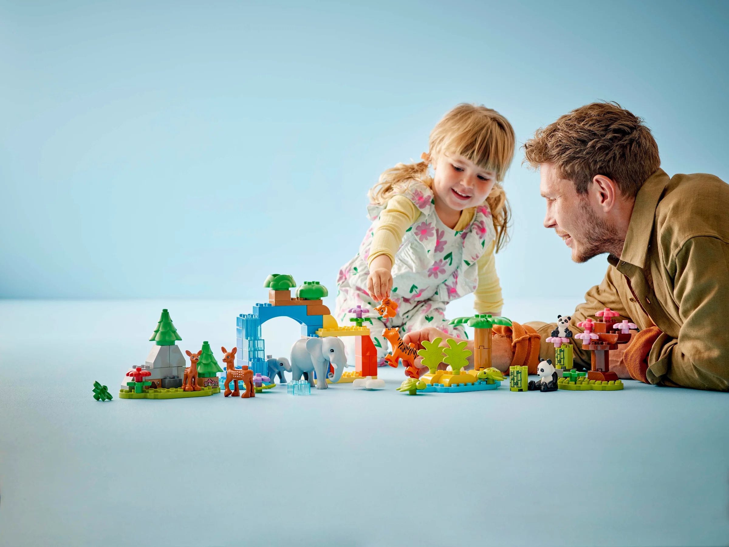 Copil și adult se joacă cu setul LEGO Duplo 10446. Atmosferă prietenoasă și creativă.