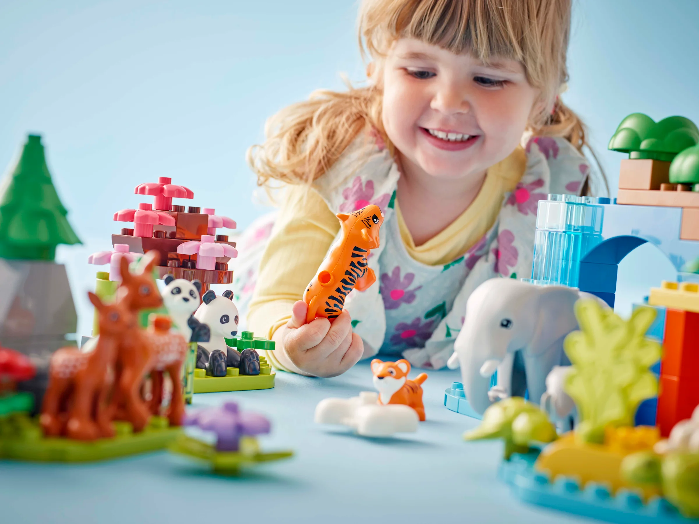 Fetiță zâmbitoare se joacă cu animalele sălbatice LEGO Duplo. Set de joacă interactiv și distractiv.