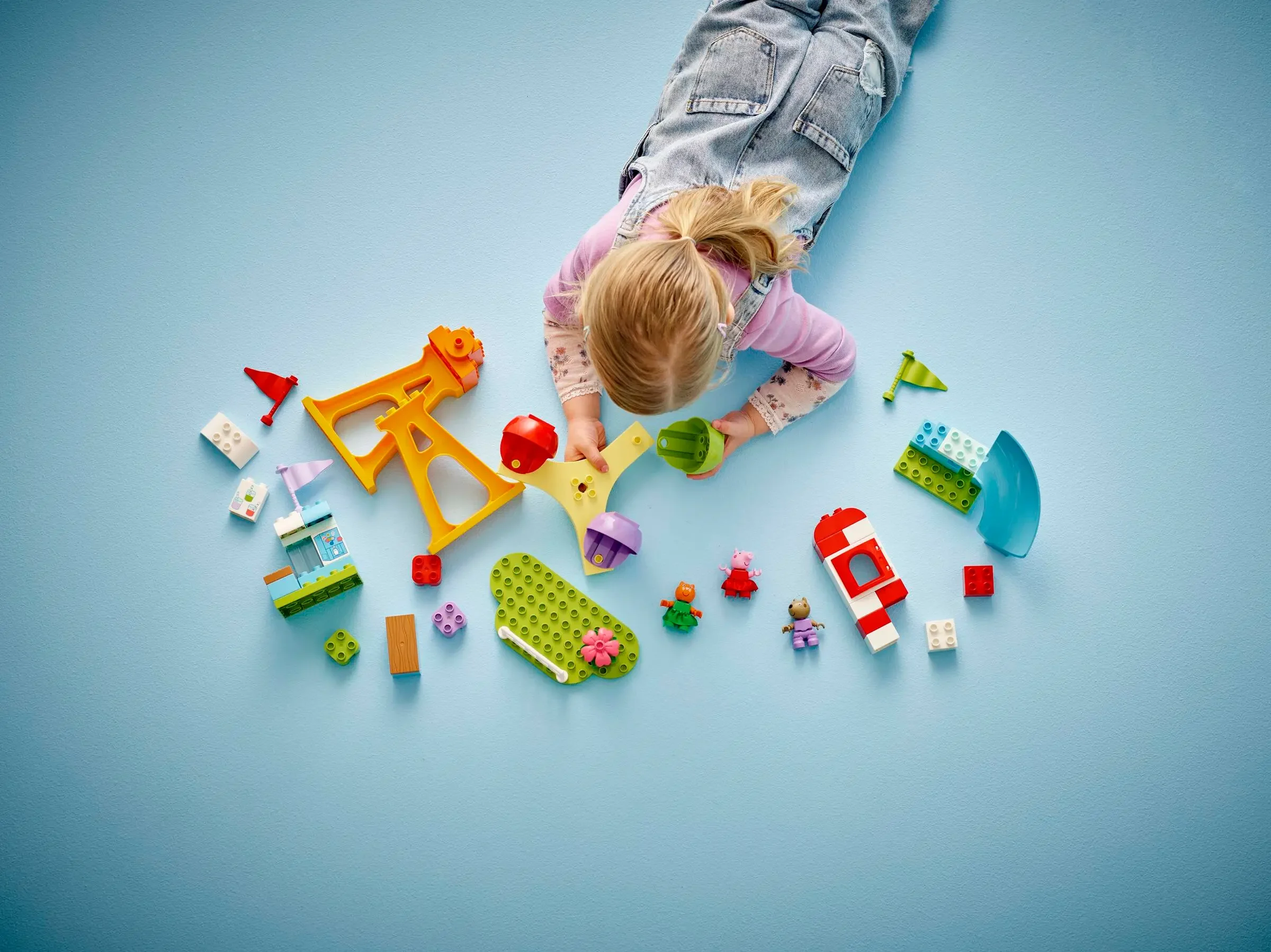 Fetiță joacă cu setul Duplo Funfair, construind și explorând lumea colorată a parcului de distracții.