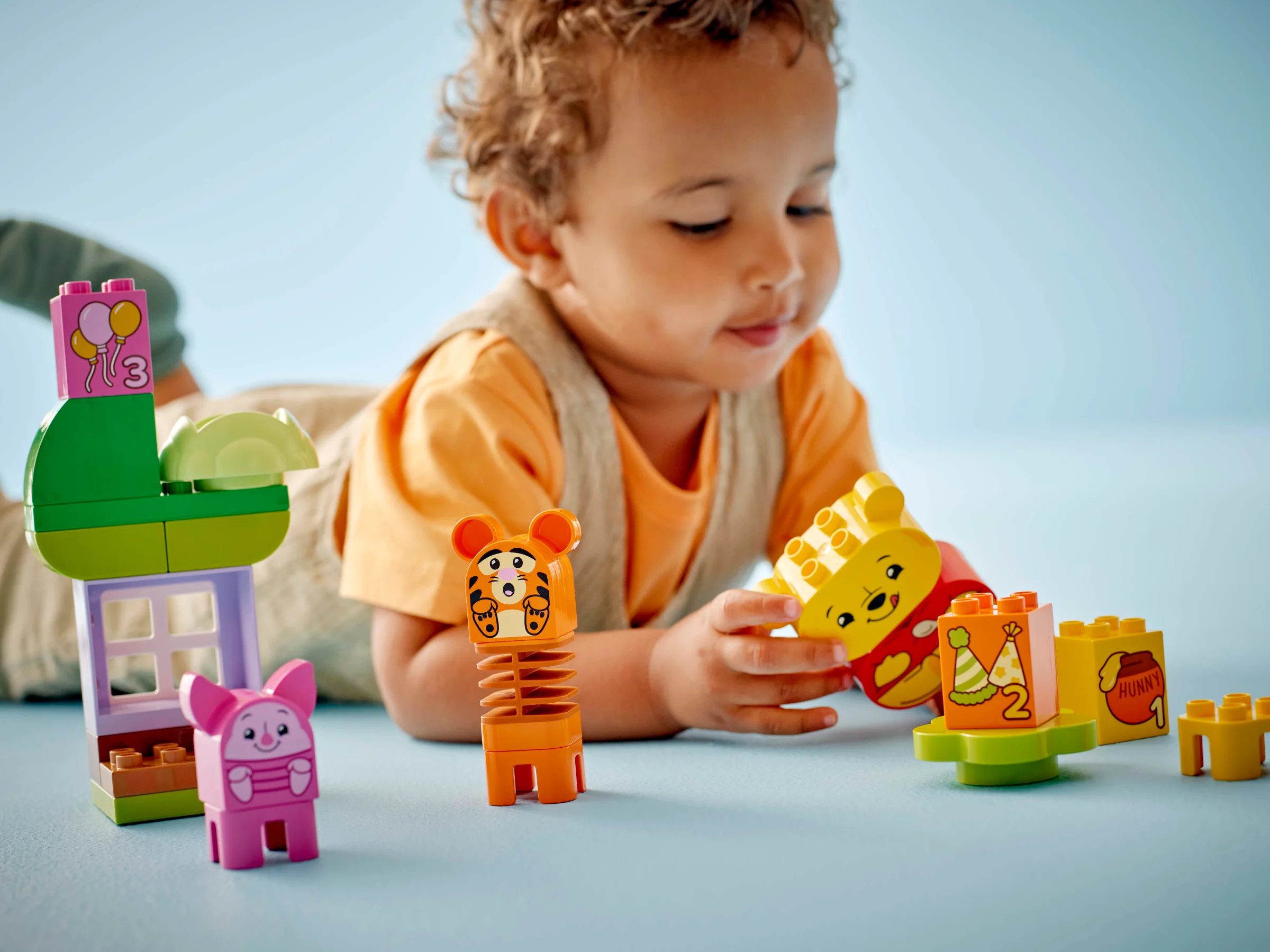 Copil se joacă cu setul LEGO Duplo Winnie the Pooh. Personaje și accesorii colorate.