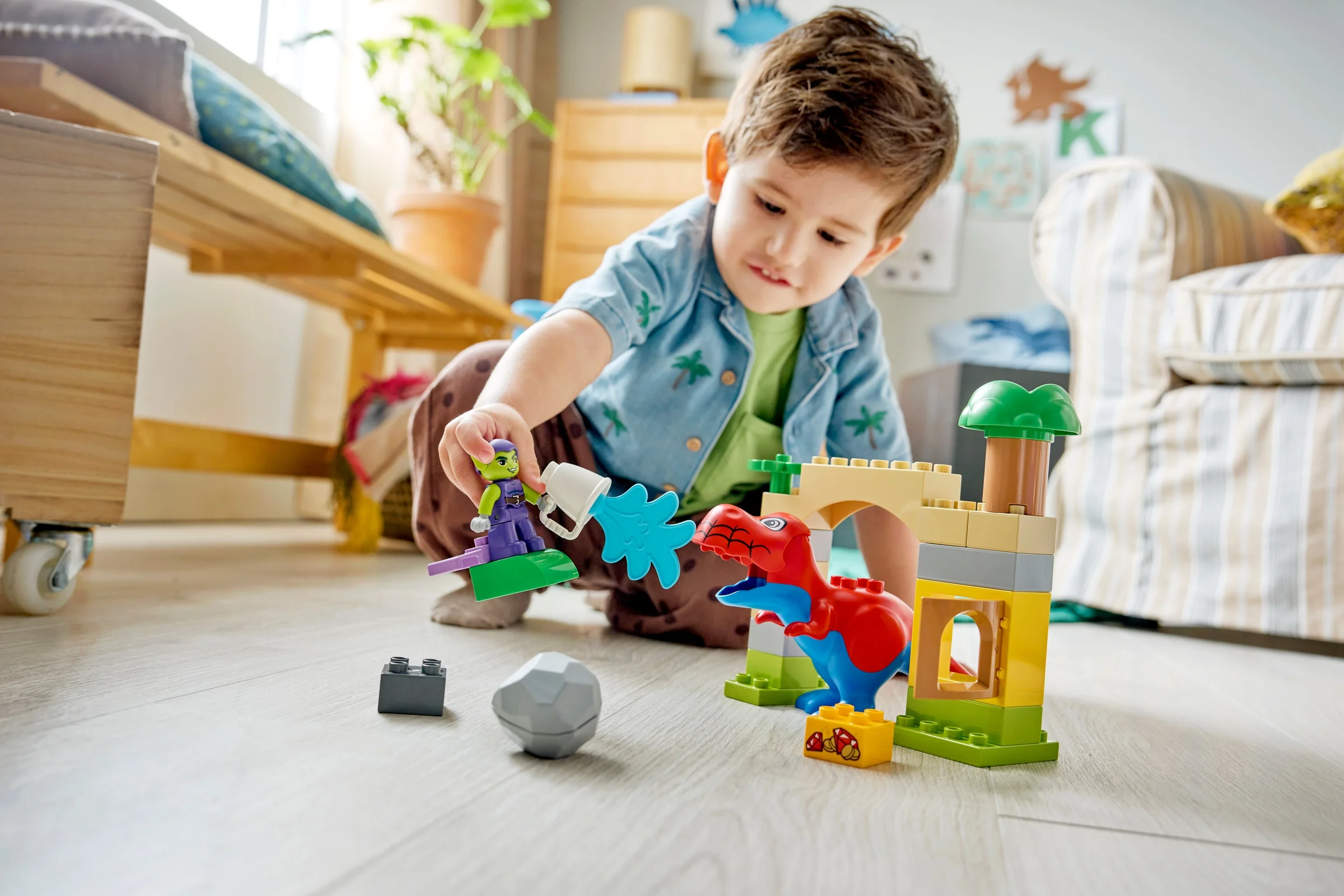 Băiat se joacă cu setul LEGO Duplo Spidey-Rex vs. Green Goblin, explorând creativitatea.