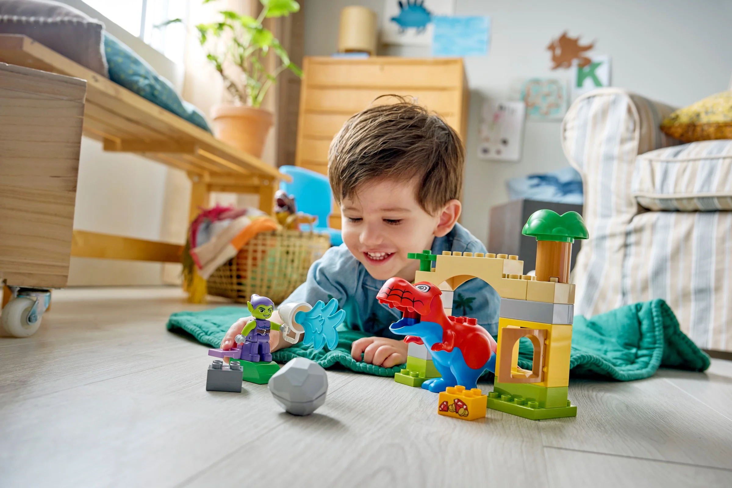 Copil zâmbind jucându-se cu setul Duplo Spidey-Rex vs. Green Goblin.