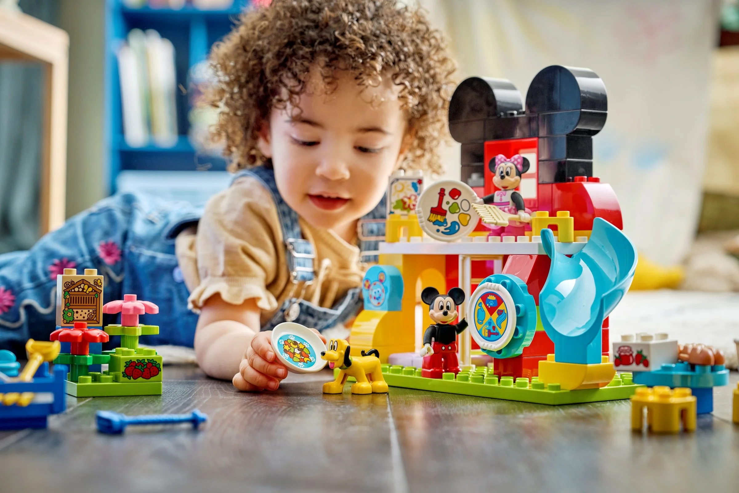 Copil se joacă cu setul LEGO Duplo Mickey Mouse Clubhouse, explorând personajele și structurile colorate.