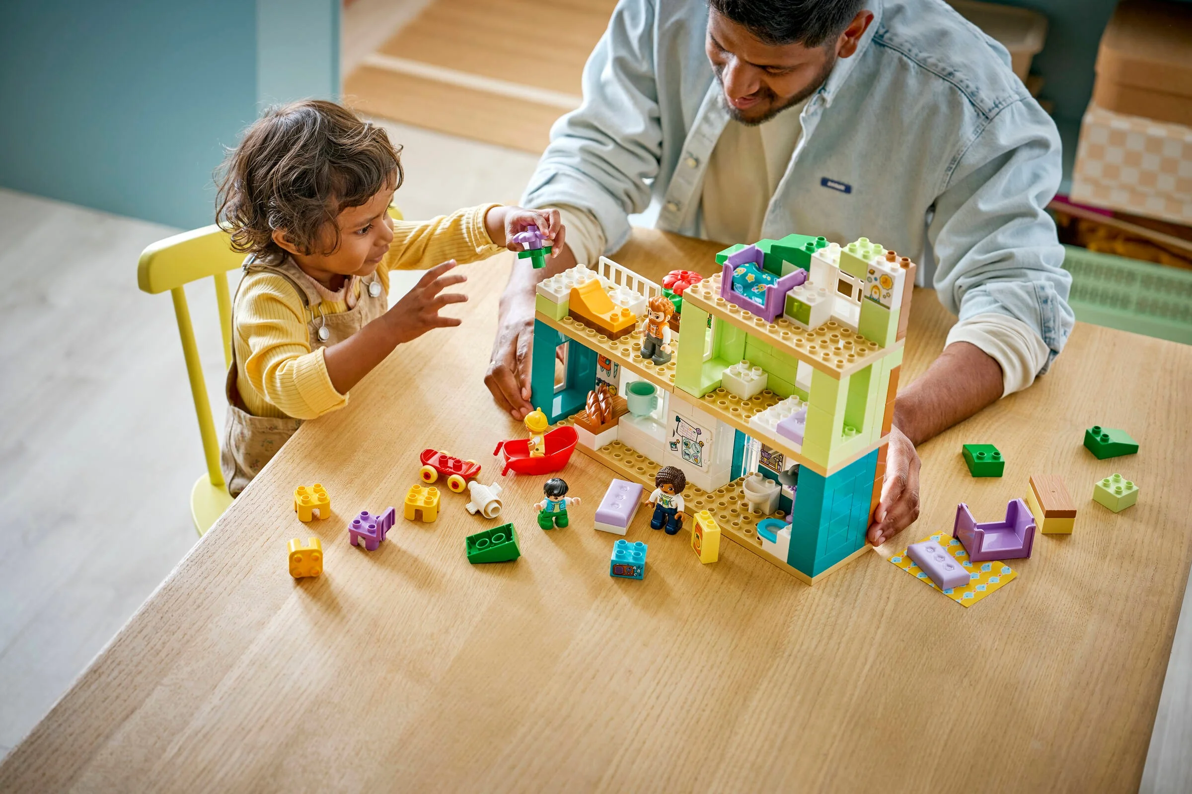 Copil construind casa modernă Duplo 10470 cu un adult. Momente creative și distractive împreună.