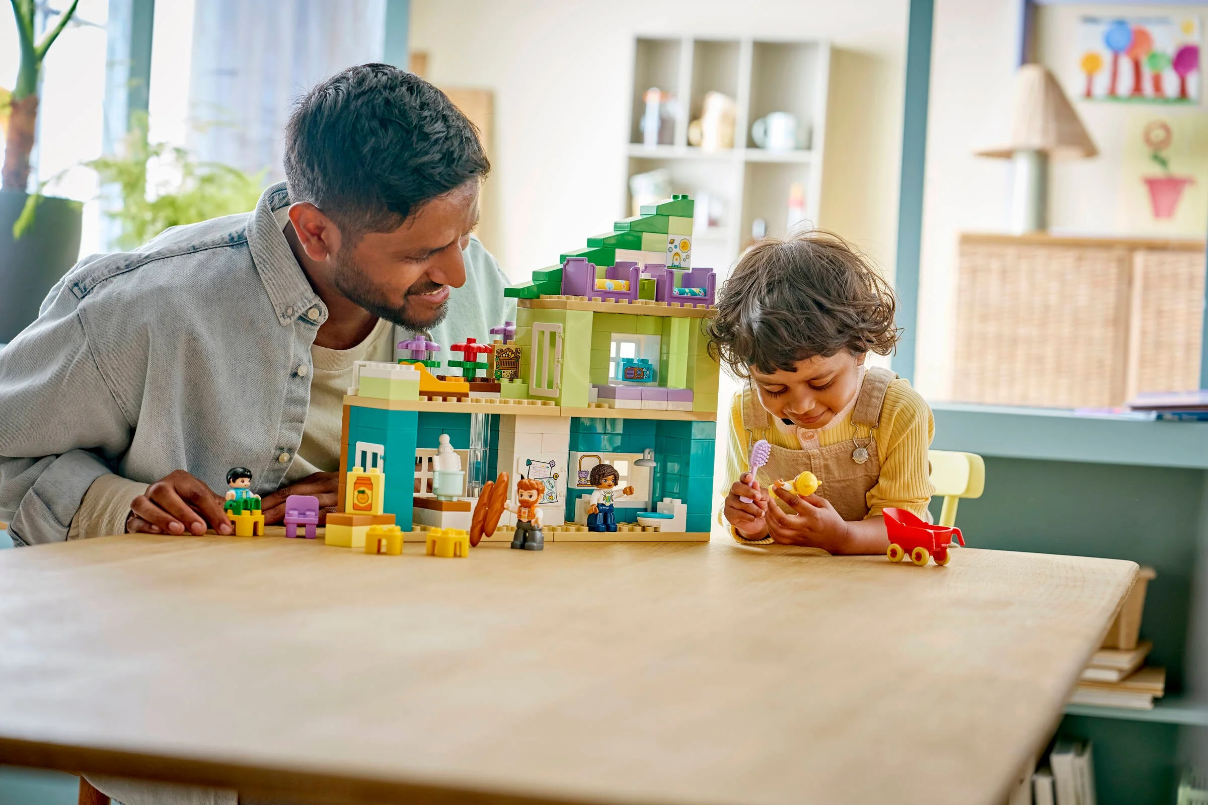 Un tată și copilul său se joacă cu setul Duplo 10470, Modern Family House. Copilul manevrează o periuță de dinți și o păpușă.