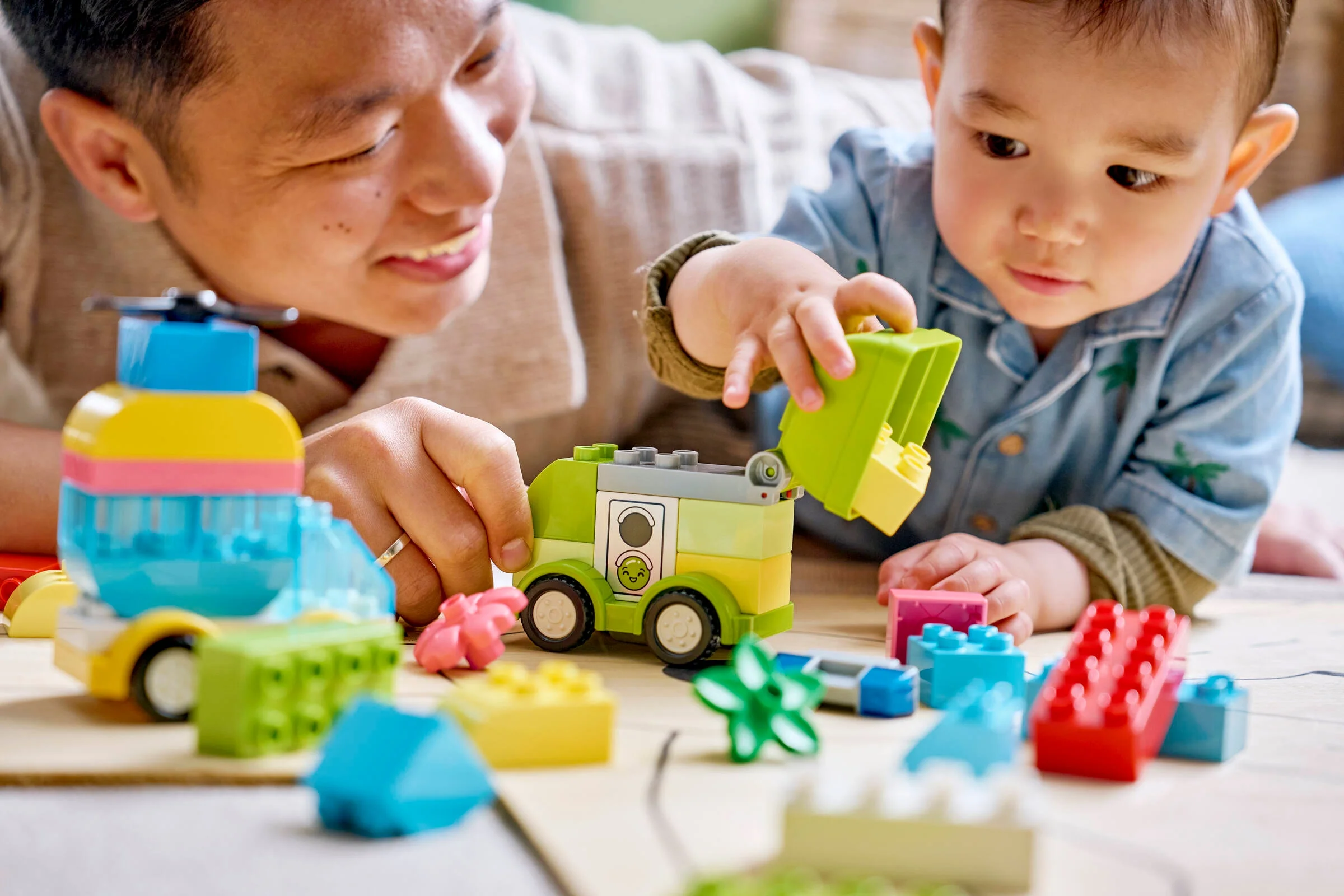 Un tată și copilul său se joacă cu setul LEGO DUPLO Creative Vehicles, construind mașinuțe colorate.