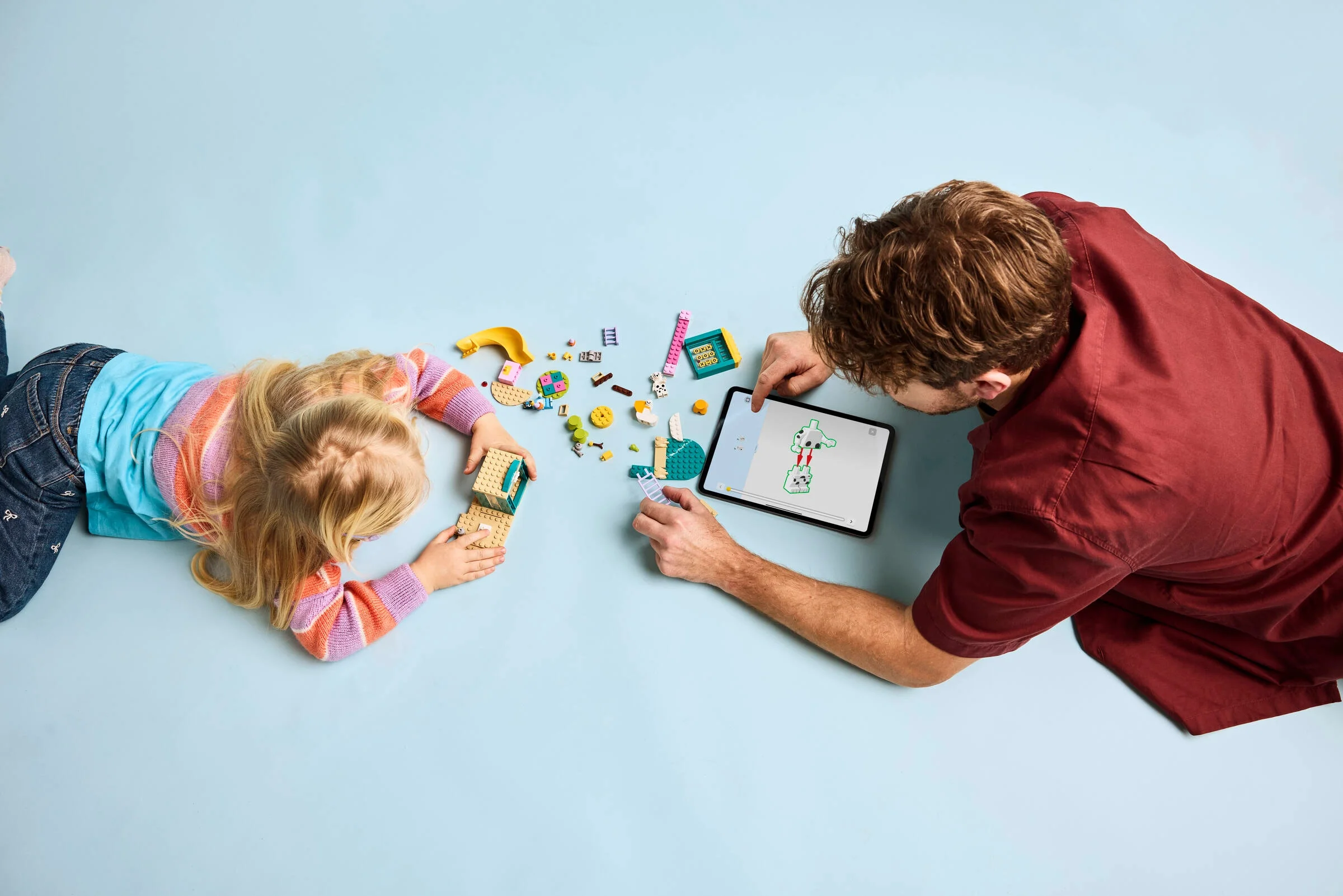 Fetiță și adult construind setul LEGO Bluey. Instrucțiuni pe tabletă, distracție garantată!