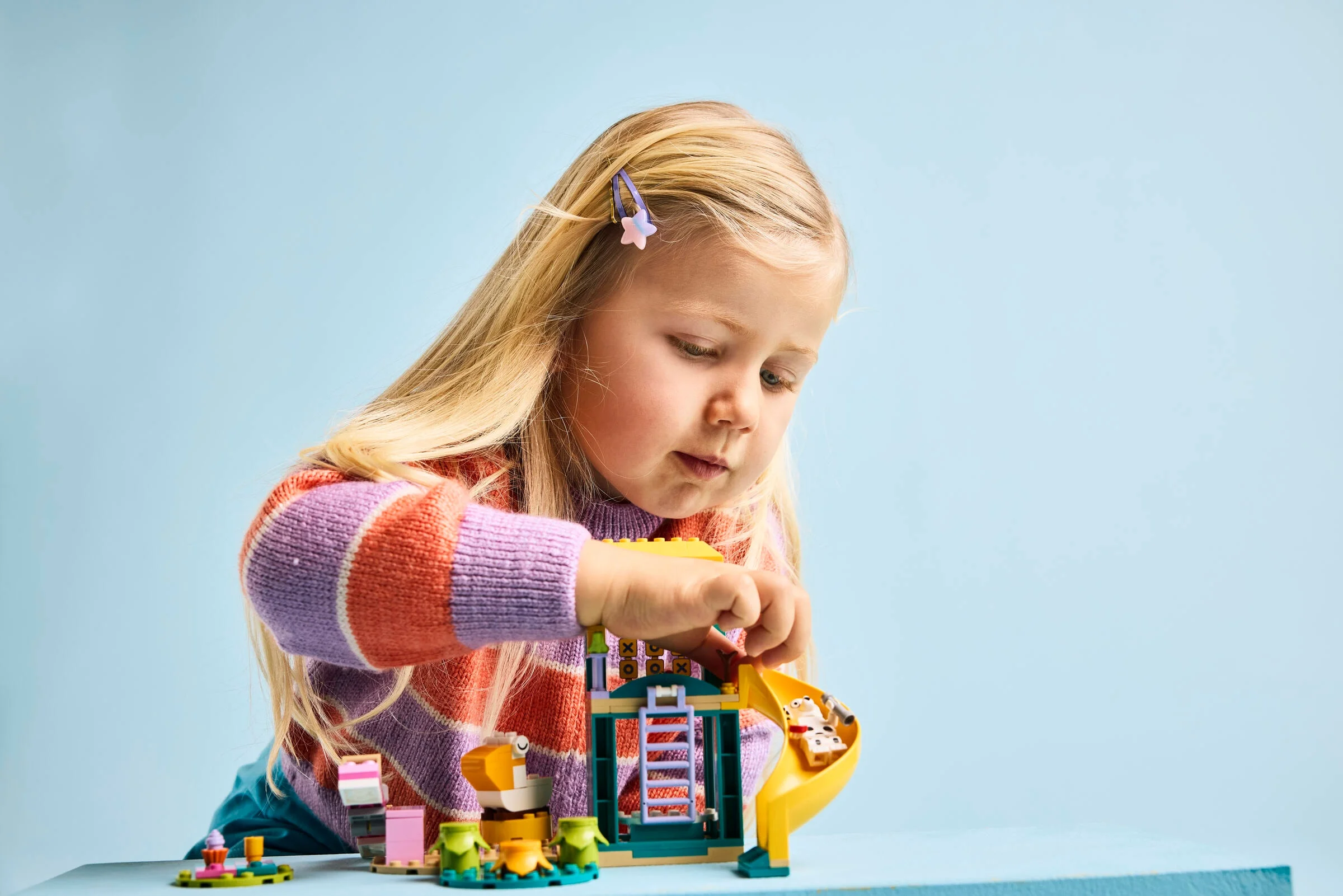 Fetiță construind setul LEGO Bluey 11201, concentrată și zâmbitoare.