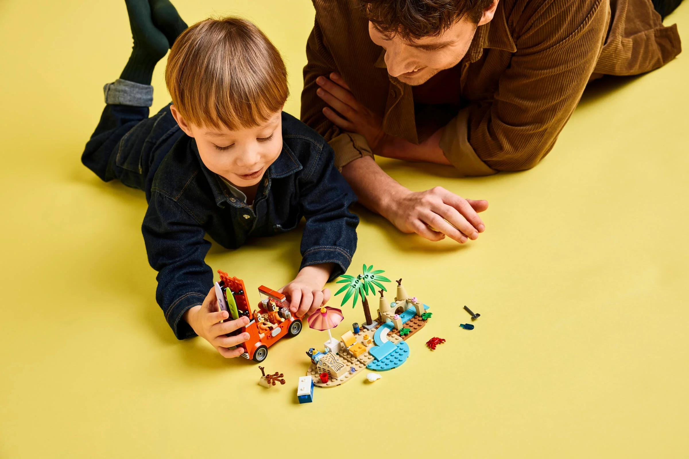 Copil și adult se joacă cu LEGO Bluey's Beach. Distracție pe plajă în familie.