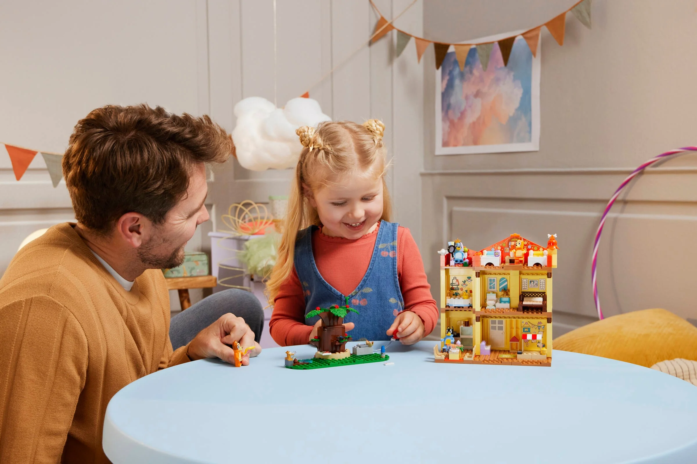 Copil și adult construind casa Bluey. Joc creativ și interacțiune familială.