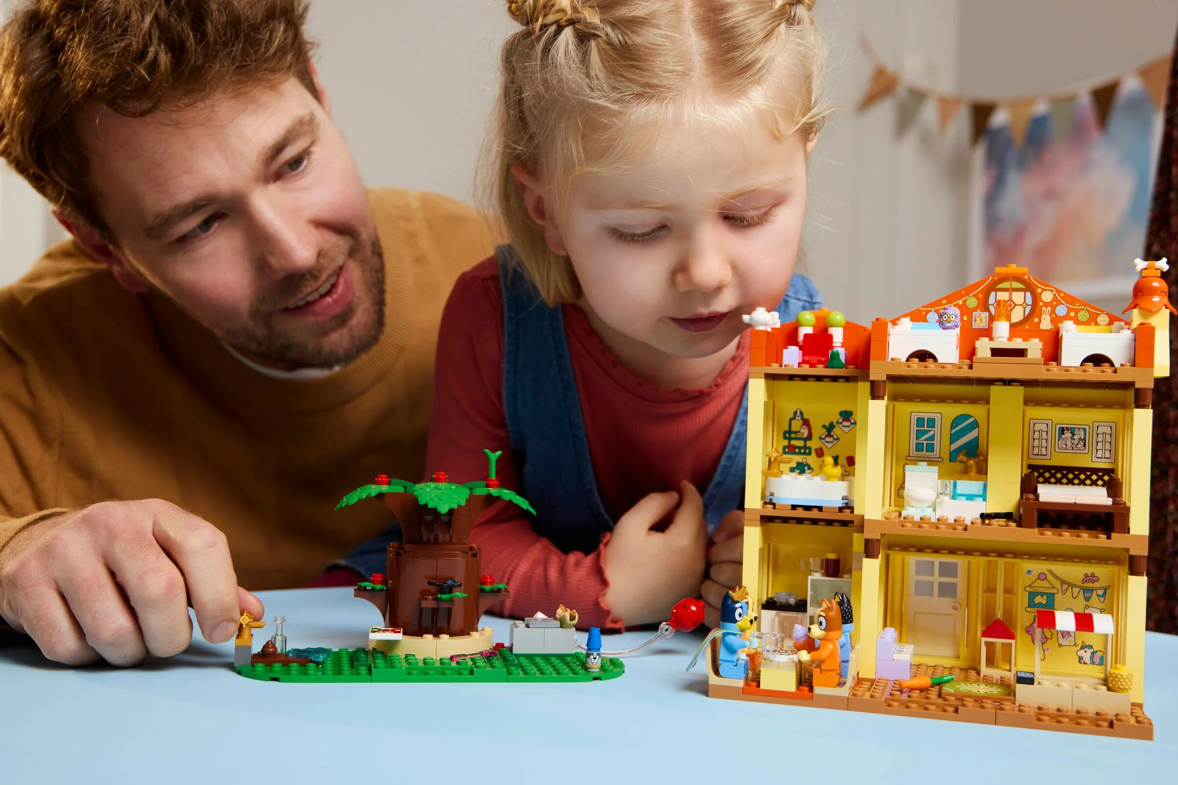 Un tată și fiica se joacă cu setul LEGO Bluey's Family House.