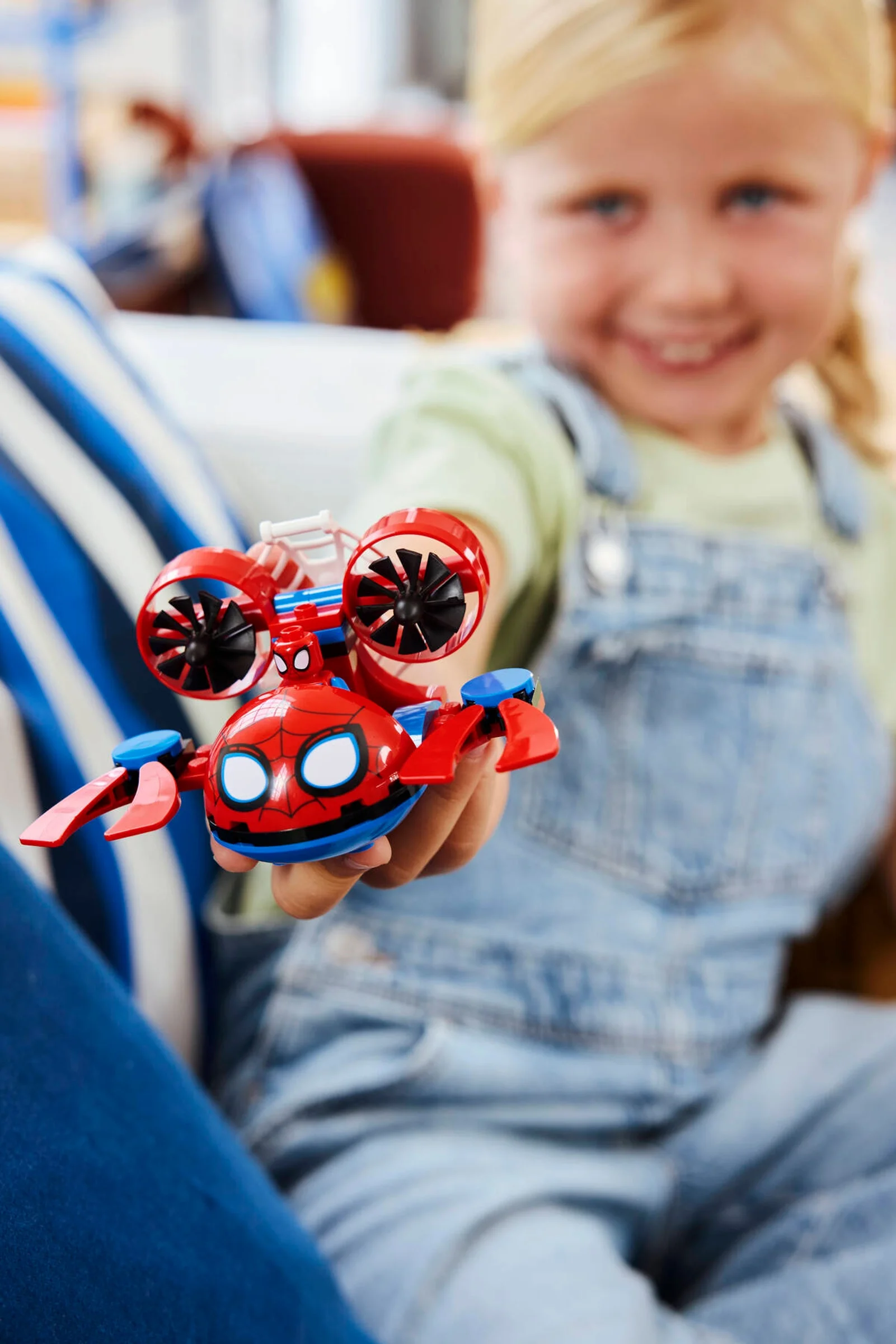 O fetiță zâmbitoare ține în mână submarinul LEGO Spidey. Joacă-te cu supereroi subacvatici!
