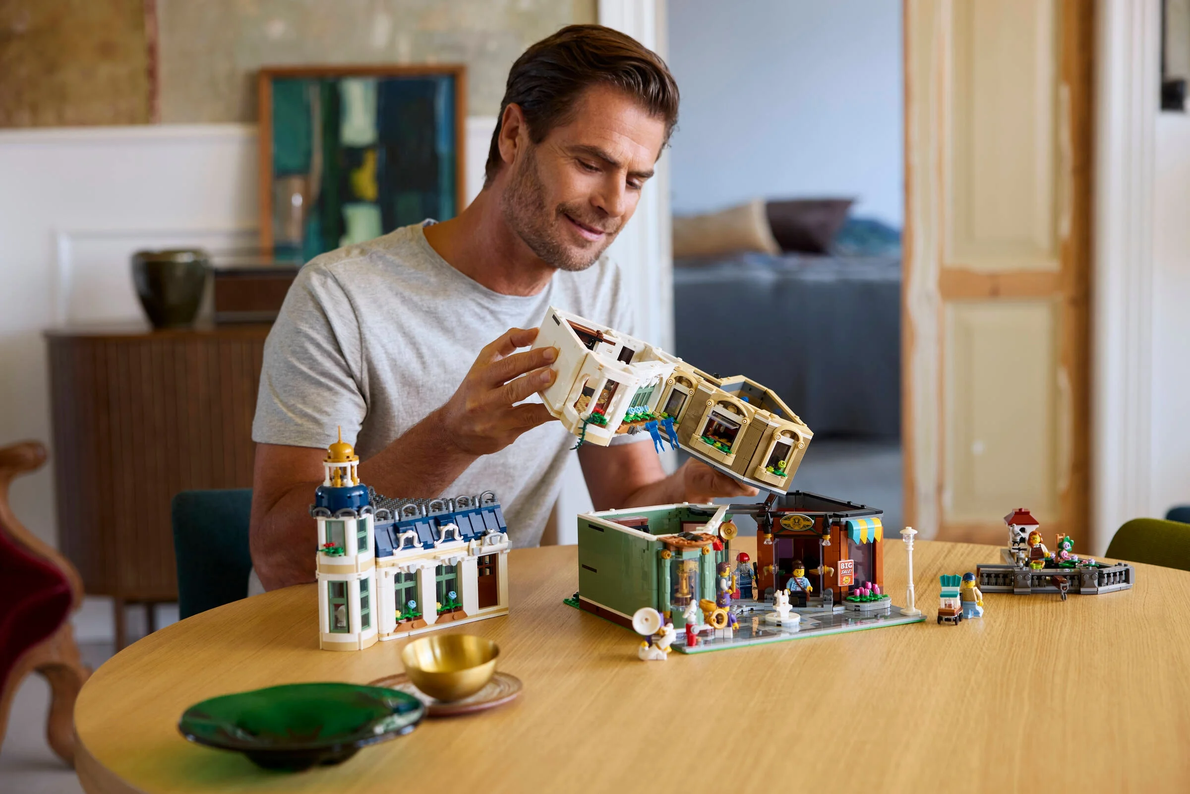 Bărbat construind strada comercială LEGO Icons 11371, arătând detaliile modelului. Imagine lifestyle.