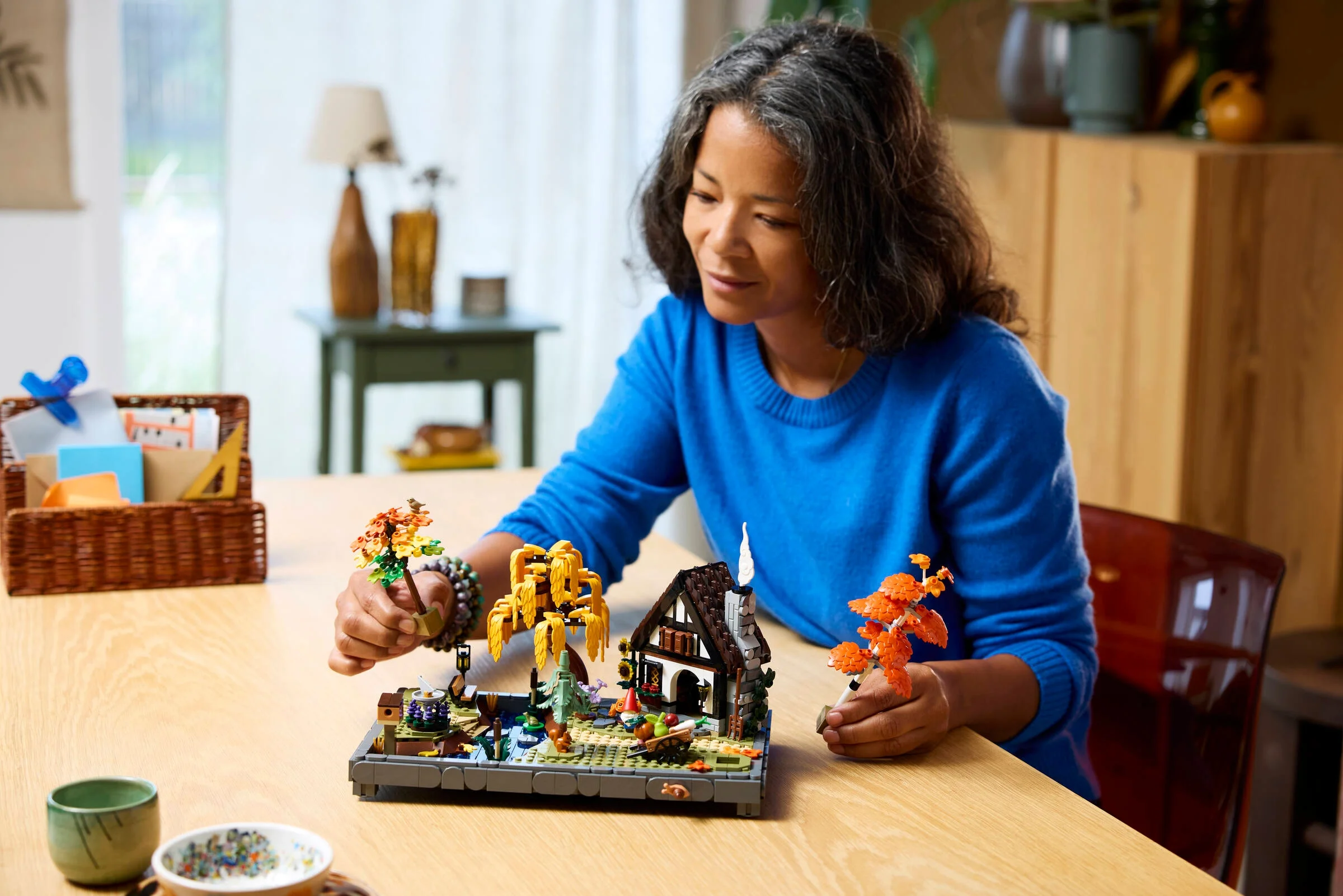 Femeie asamblând setul LEGO 11372 Grădina Căsuței de Toamnă. Detaliile sunt vizibile.