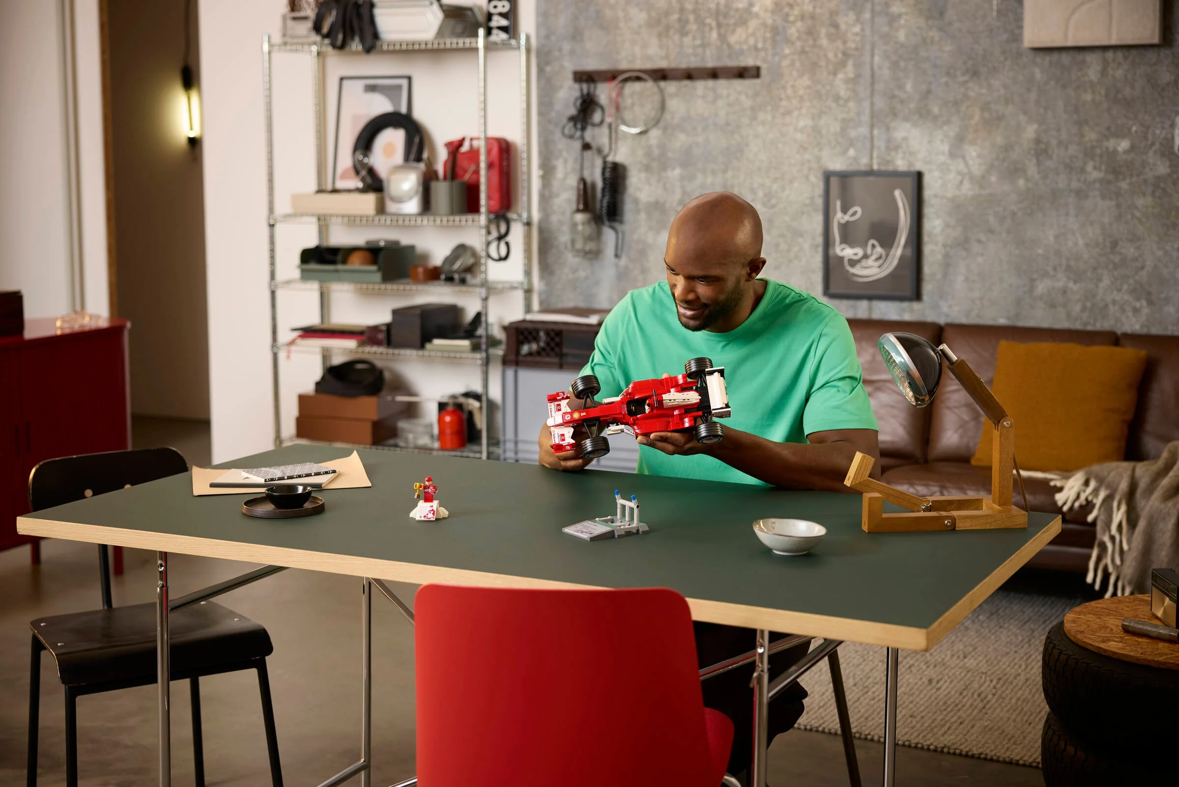 Un bărbat admiră Ferrari F2004 LEGO, într-o scenă relaxată acasă.