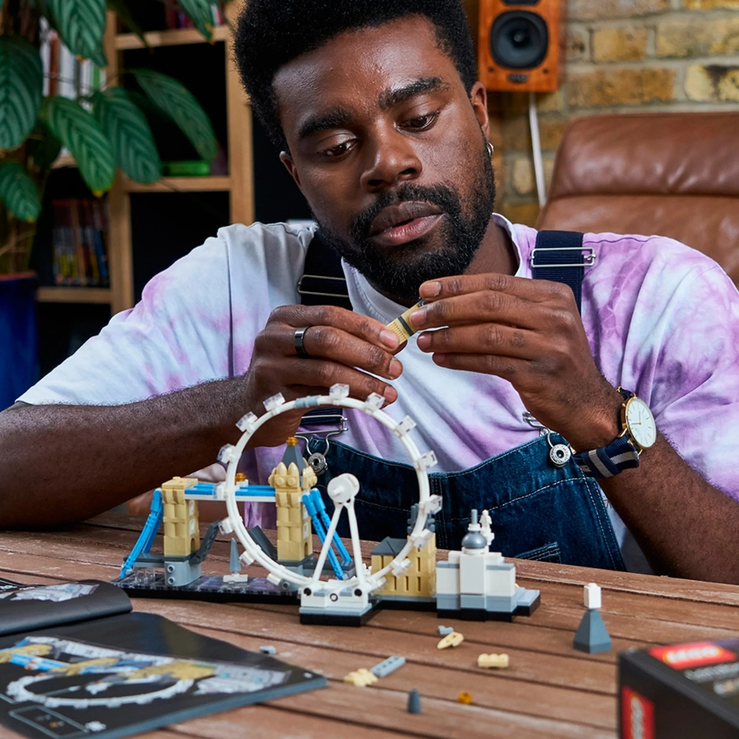 Un bărbat construiește setul LEGO Architecture Londra (21034), concentrat asupra detaliilor.